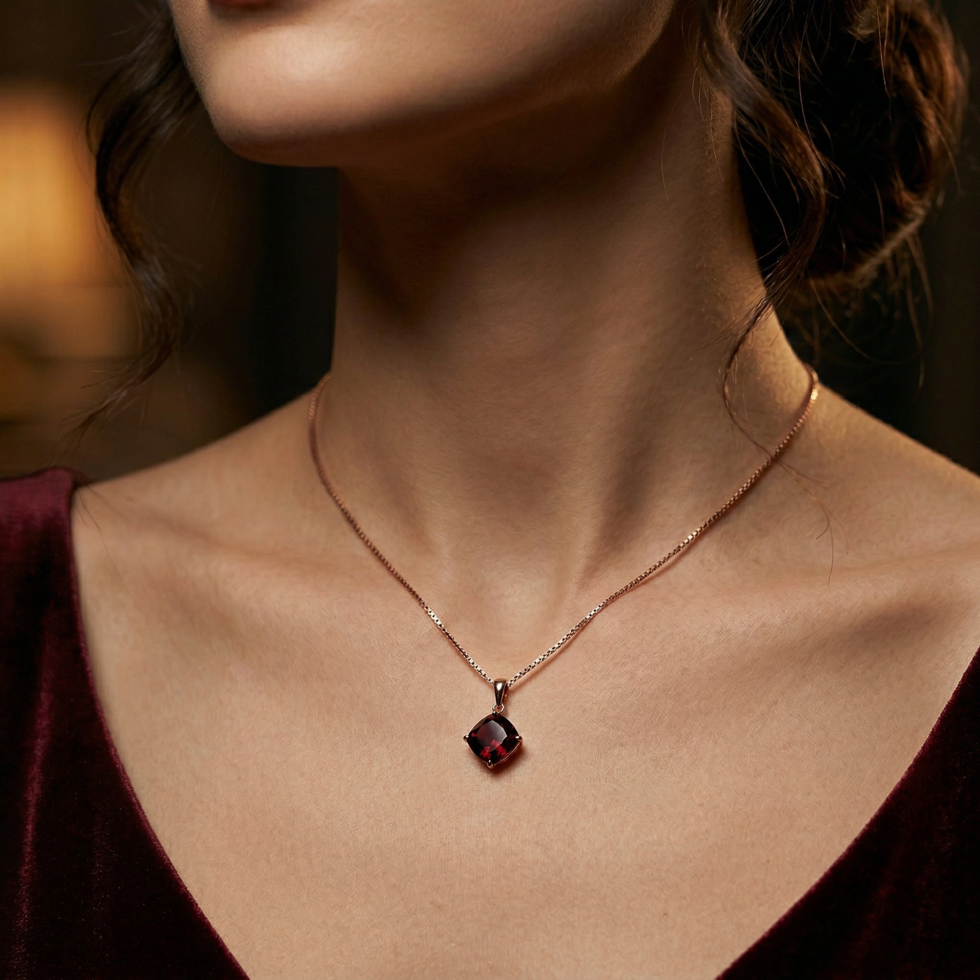Model wearing the 18K rose gold cushion cut garnet necklace, showing the pendant's scale against a velvet dress.