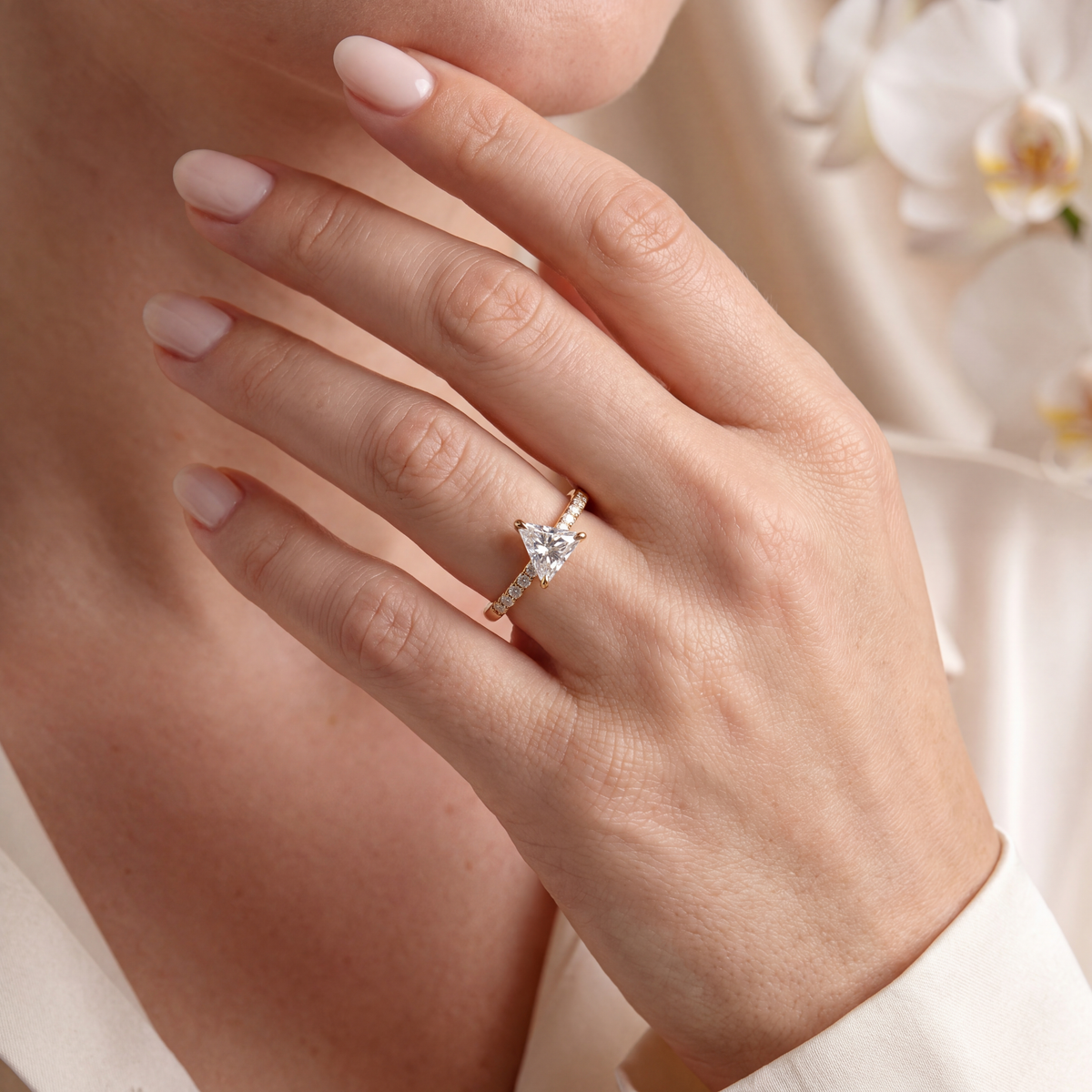 Close-up of a hand wearing the yellow gold trillion-cut moissanite ring.