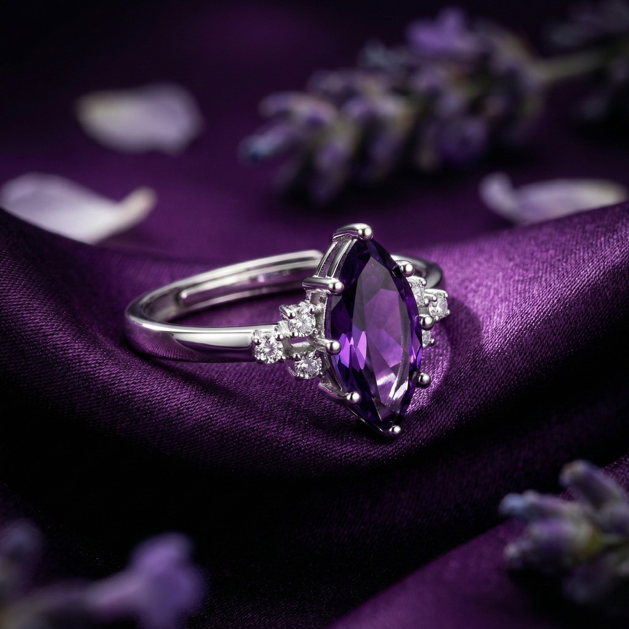 Side view detail of the marquesa cut amethyst ring and sterling silver adjustable band on purple silk.