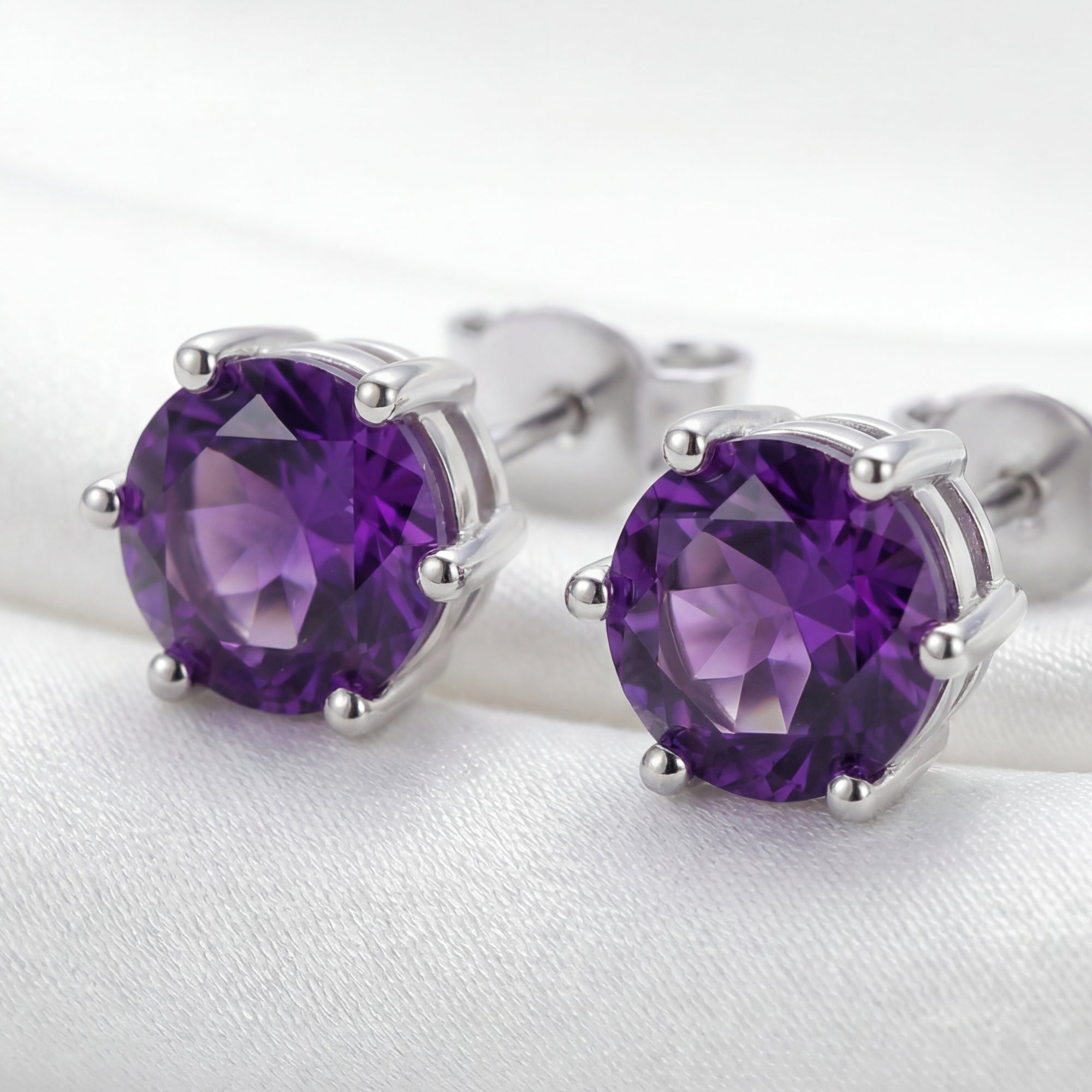 Macro shot of round cut simulated amethyst stud earrings in a 6-prong sterling silver setting.