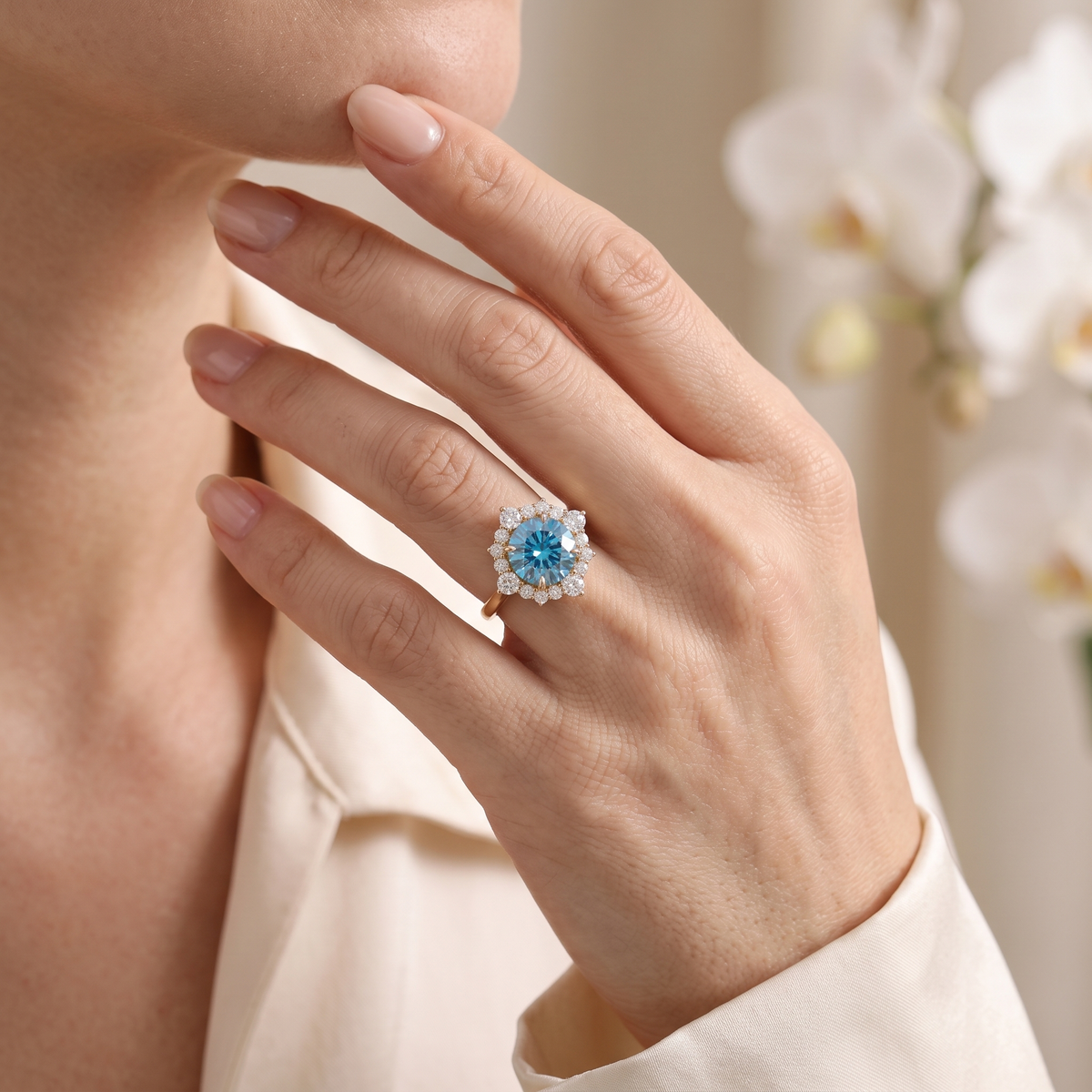 Round blue moissanite halo ring in rose gold worn on a hand.