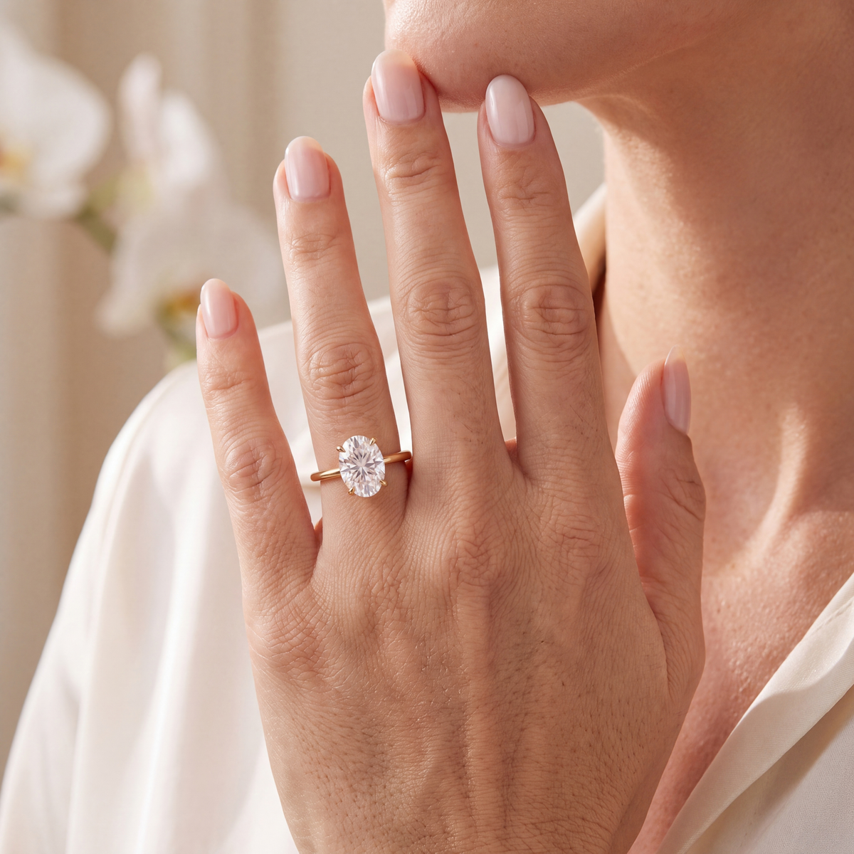 Yellow gold oval moissanite solitaire engagement ring shown on a model's hand.