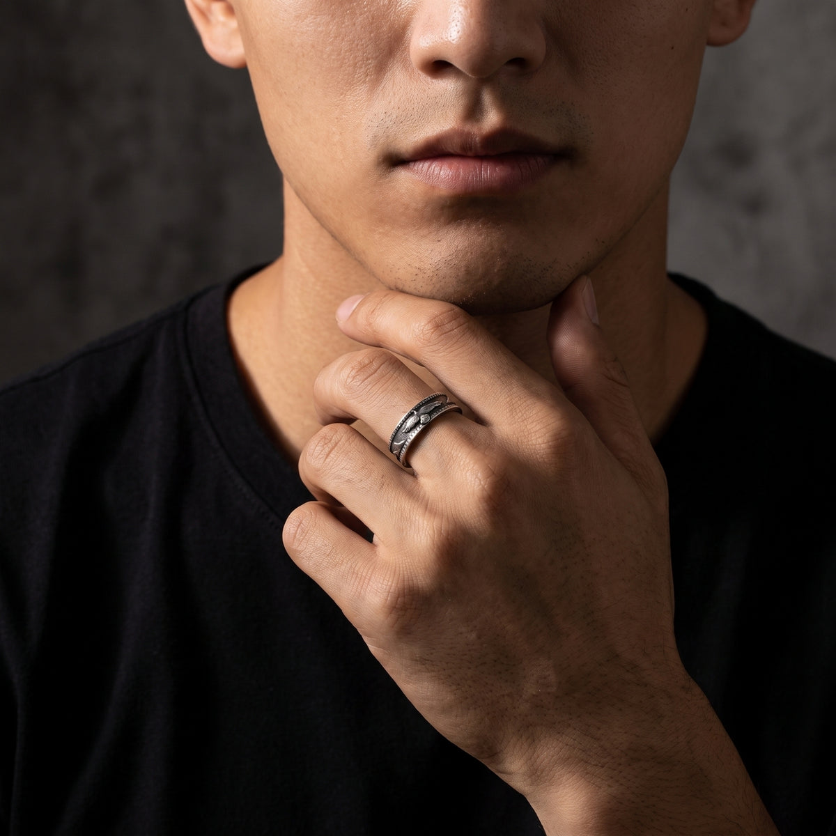 Close-up of a person wearing the silver eagle open-band ring on an index finger while resting a hand under the chin.