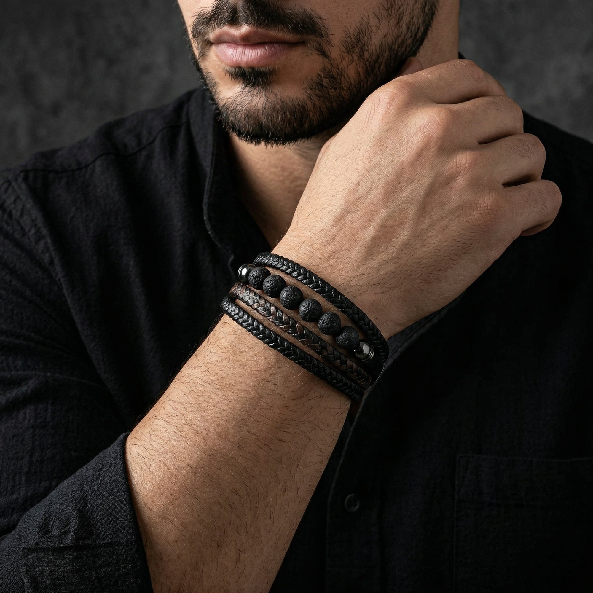 Close-up of a man wearing the black braided leather and lava stone Outrider bracelet on his wrist.