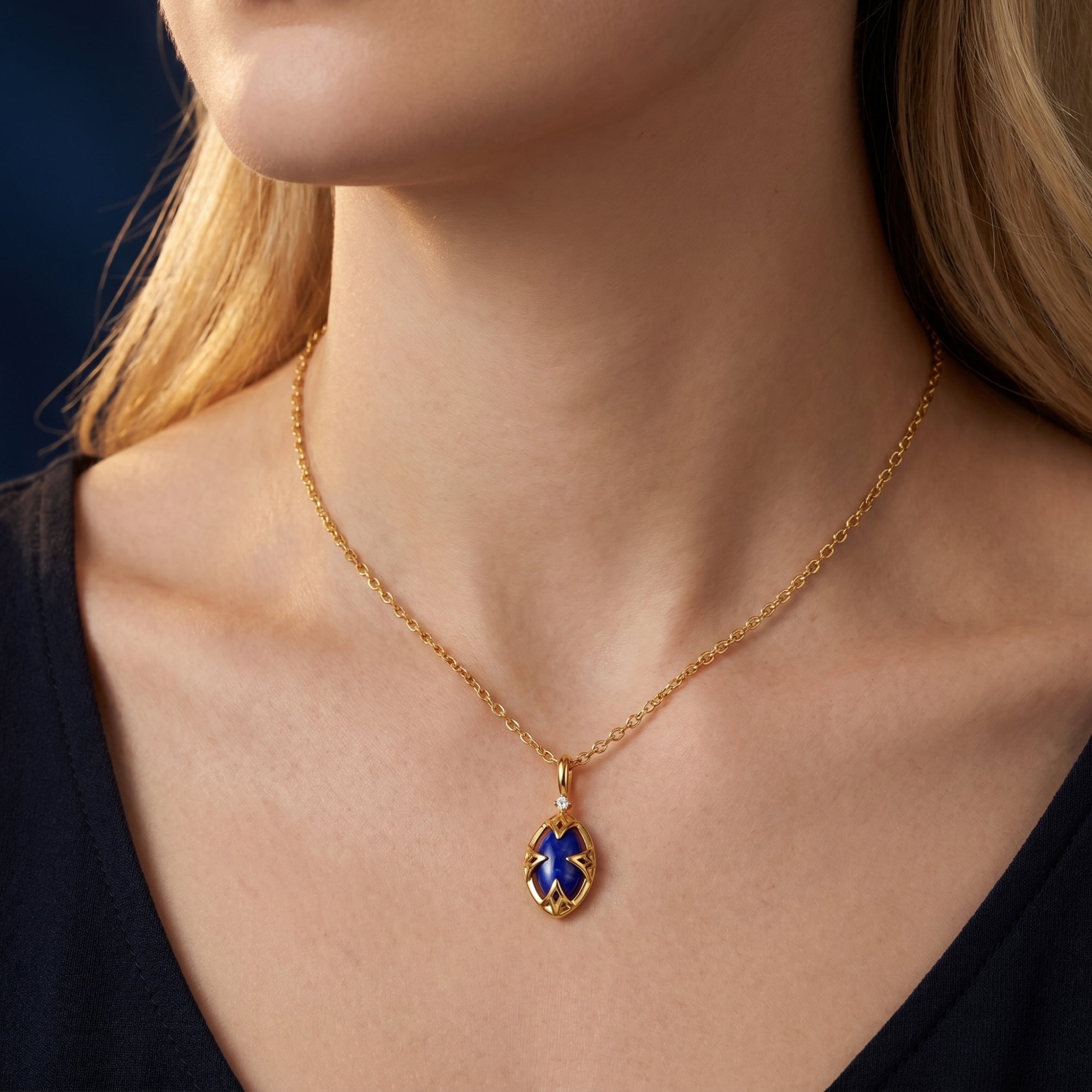 Yellow gold marquise natural lapis lazuli necklace worn by a model against a dark top.