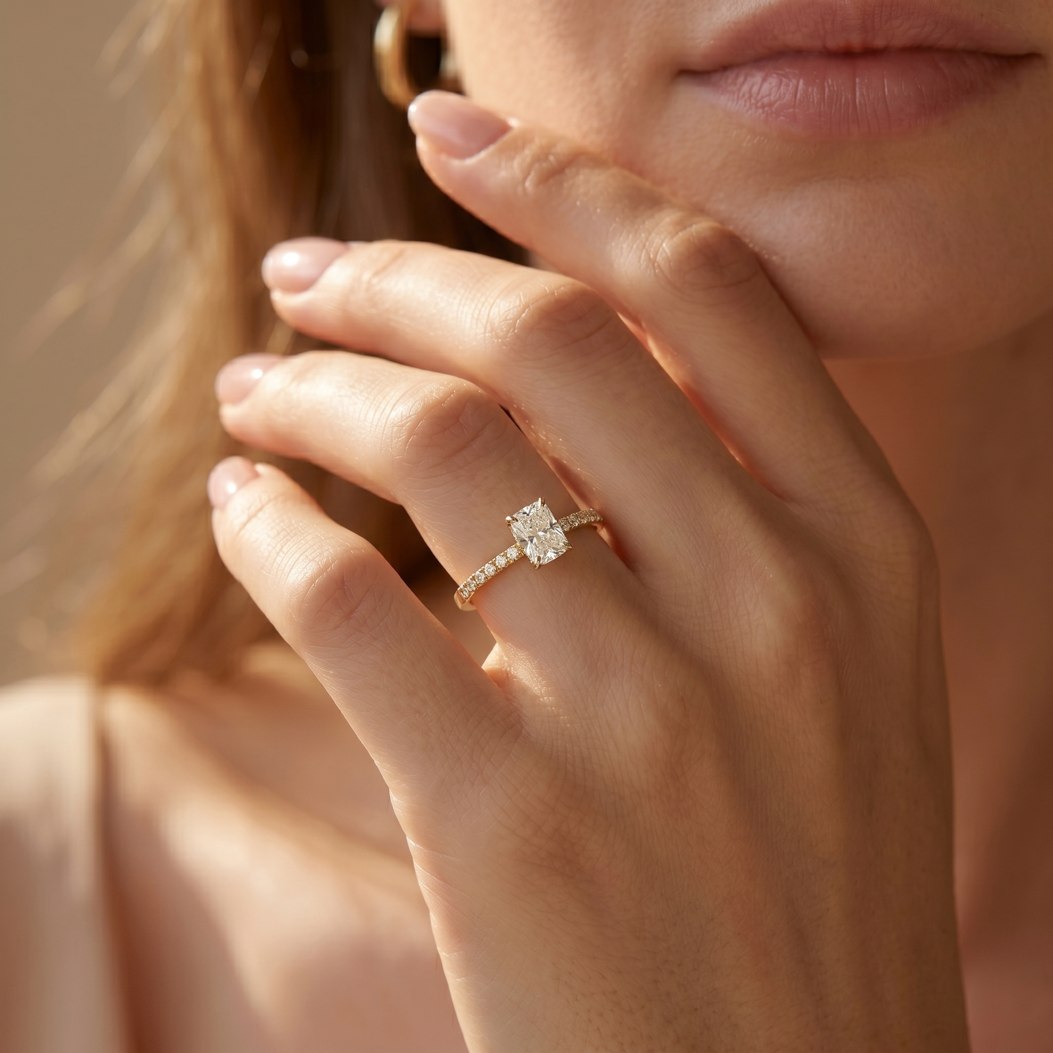 A model wearing a yellow gold cushion cut moissanite engagement ring with a pavé band on her ring finger.