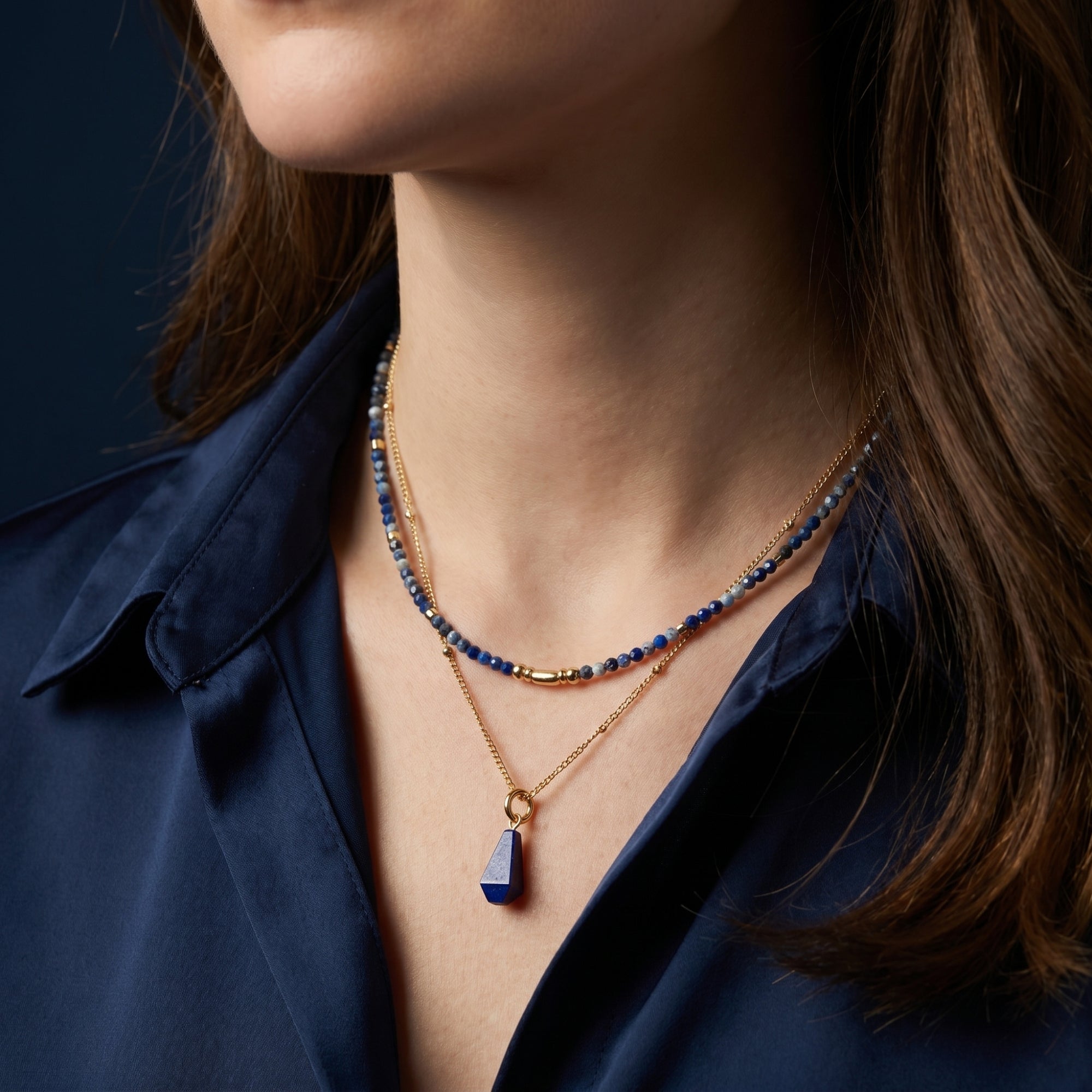 Woman wearing the gold layered Azure Cascade necklace with blue lapis beads and an irregular pendant.