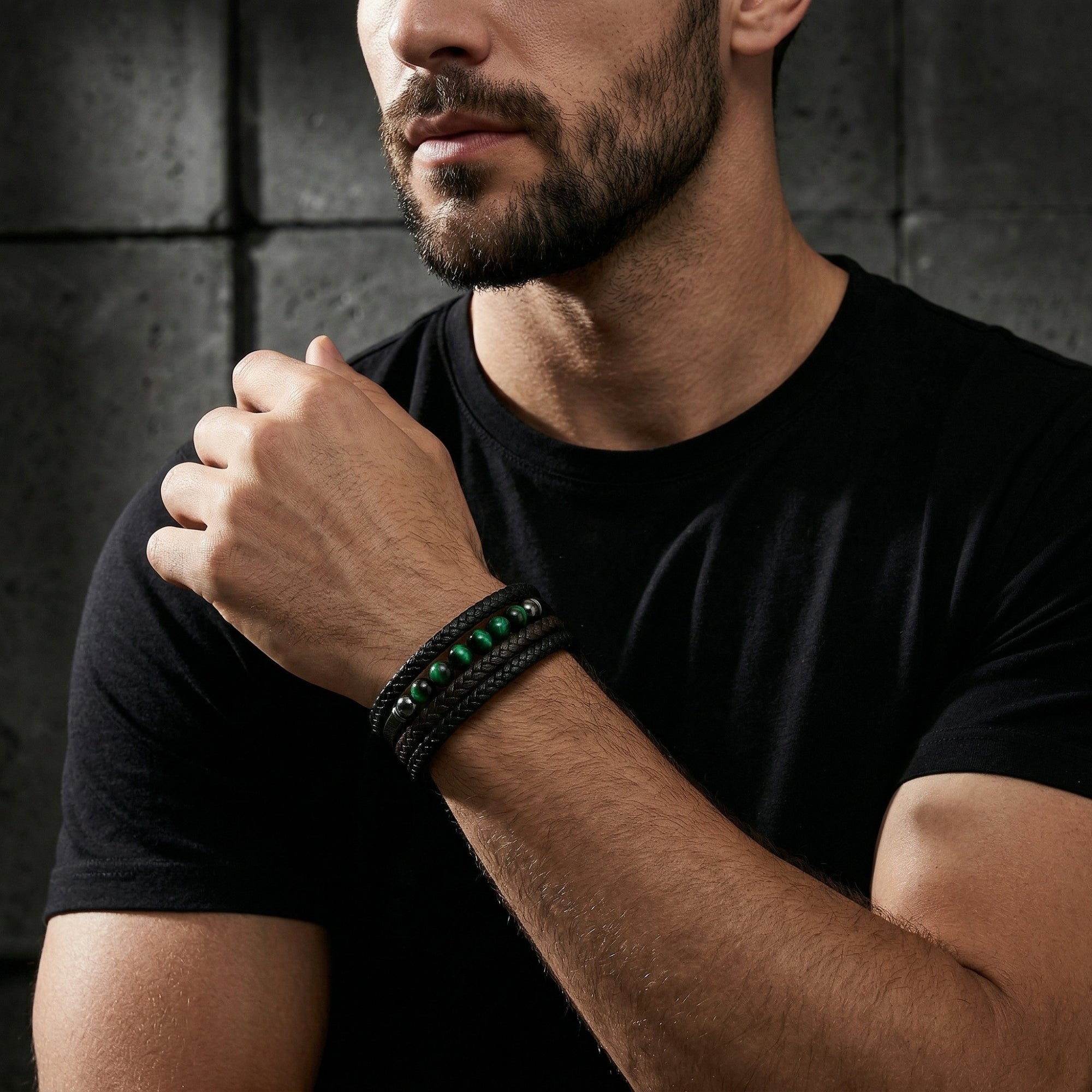 Men's multi-strand black leather bracelet with green tiger eye beads worn on a model's wrist.