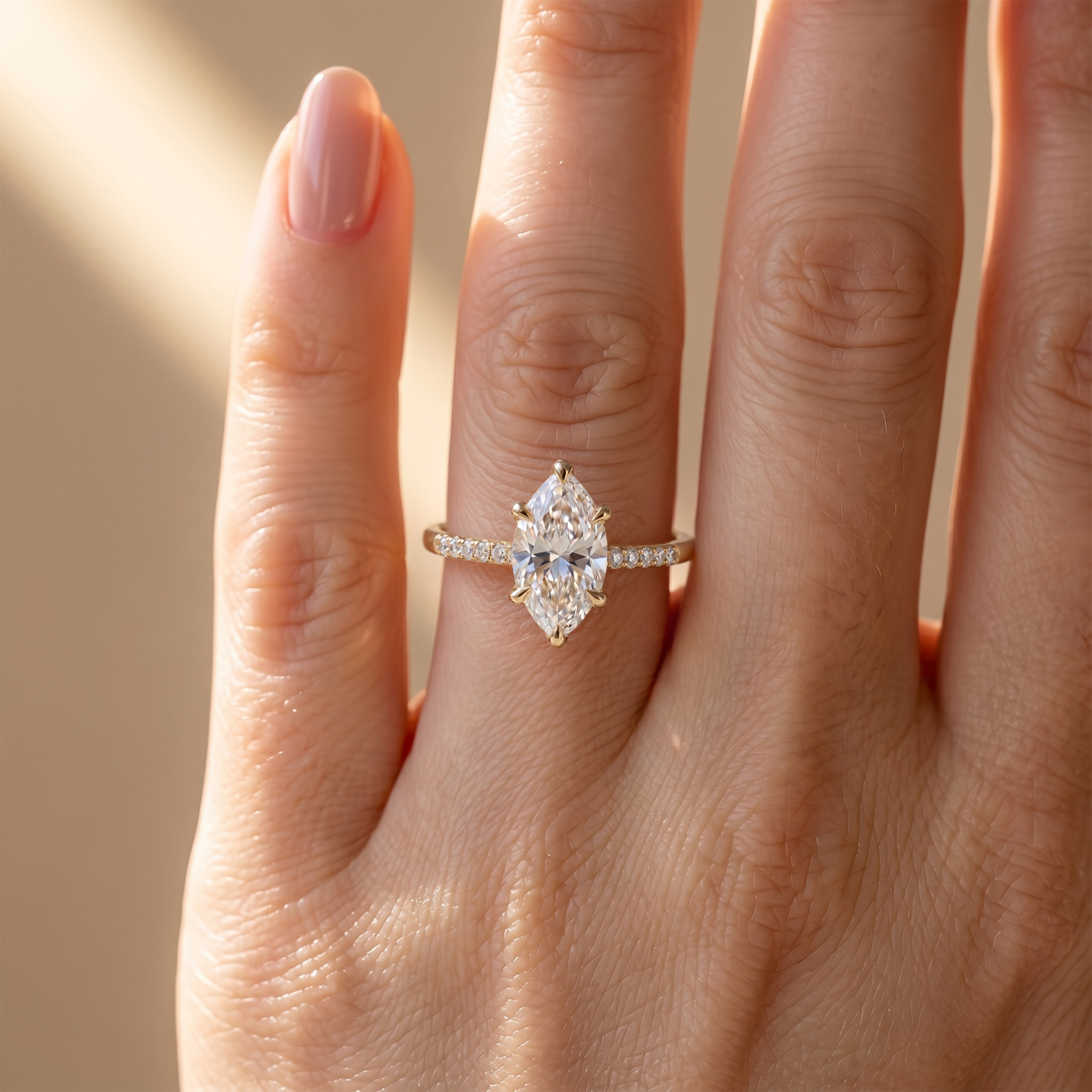 Close-up of a woman's hand wearing a delicate yellow gold marquise-cut moissanite ring with a diamond band.