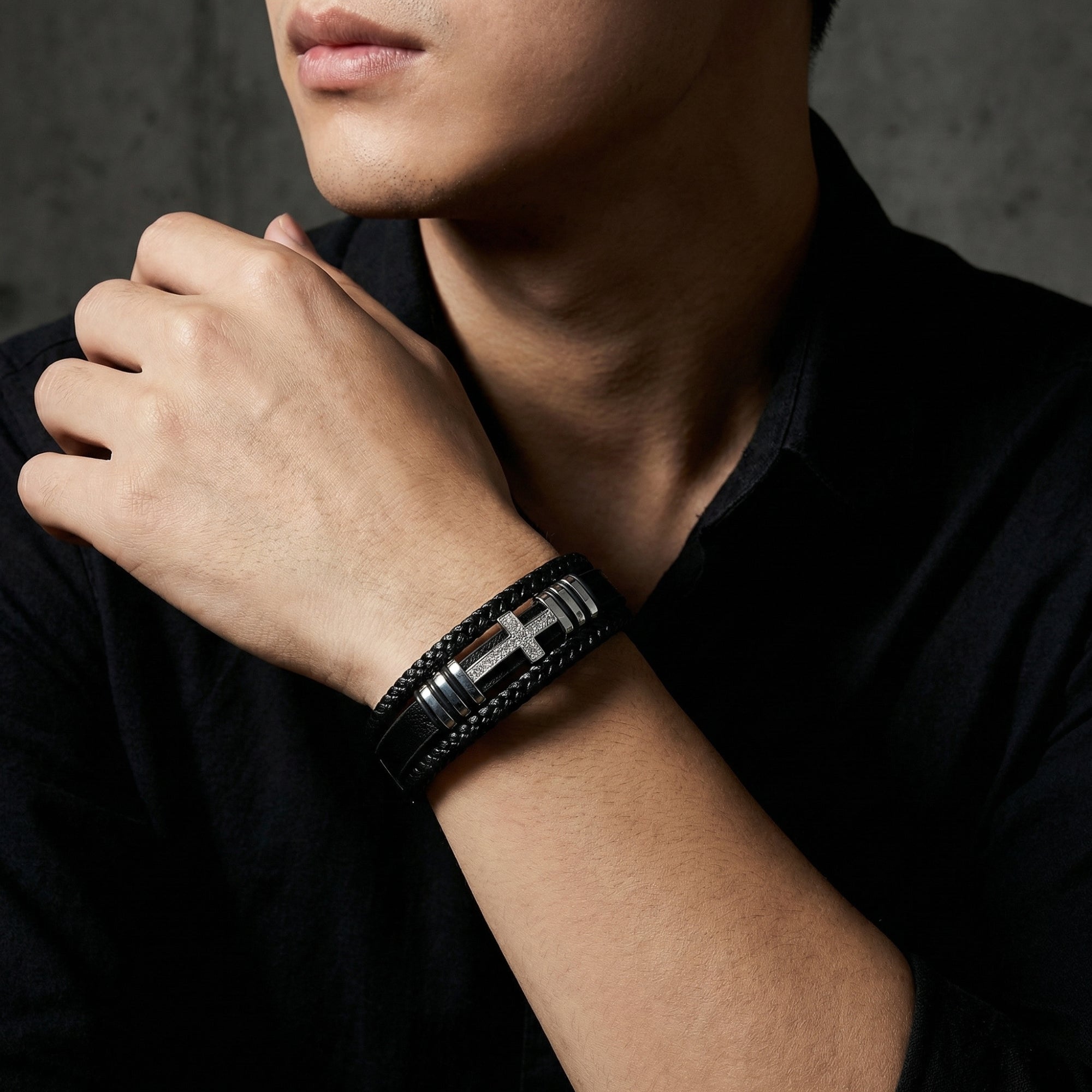 Men's Aegis Cross Bracelet in black leather and stainless steel worn on a wrist with a black shirt.