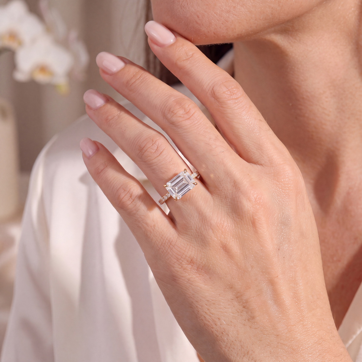 Model wearing a yellow gold east-west emerald-cut moissanite ring on her hand.