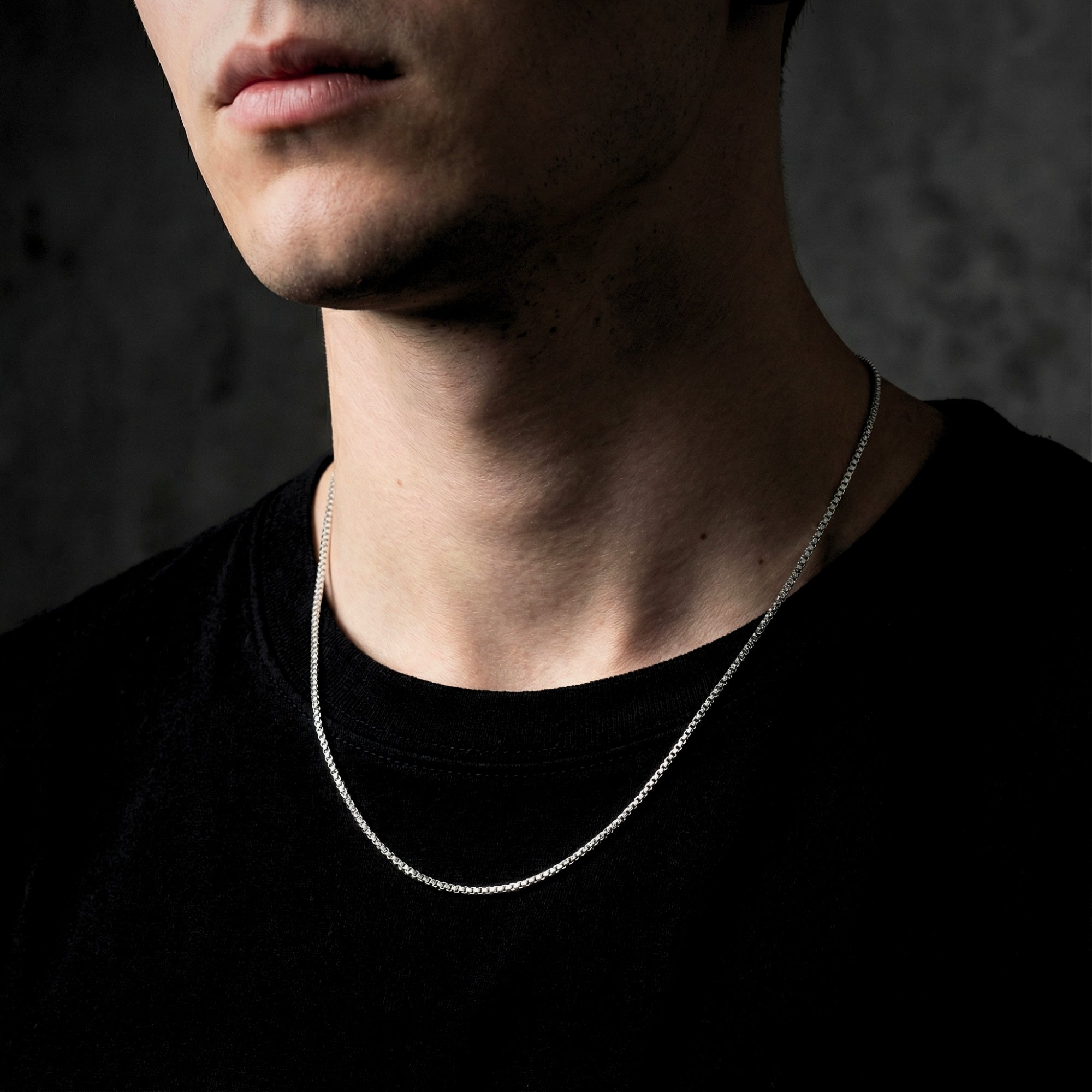 Male model wearing a silver stainless steel boxer chain necklace over a black t-shirt.