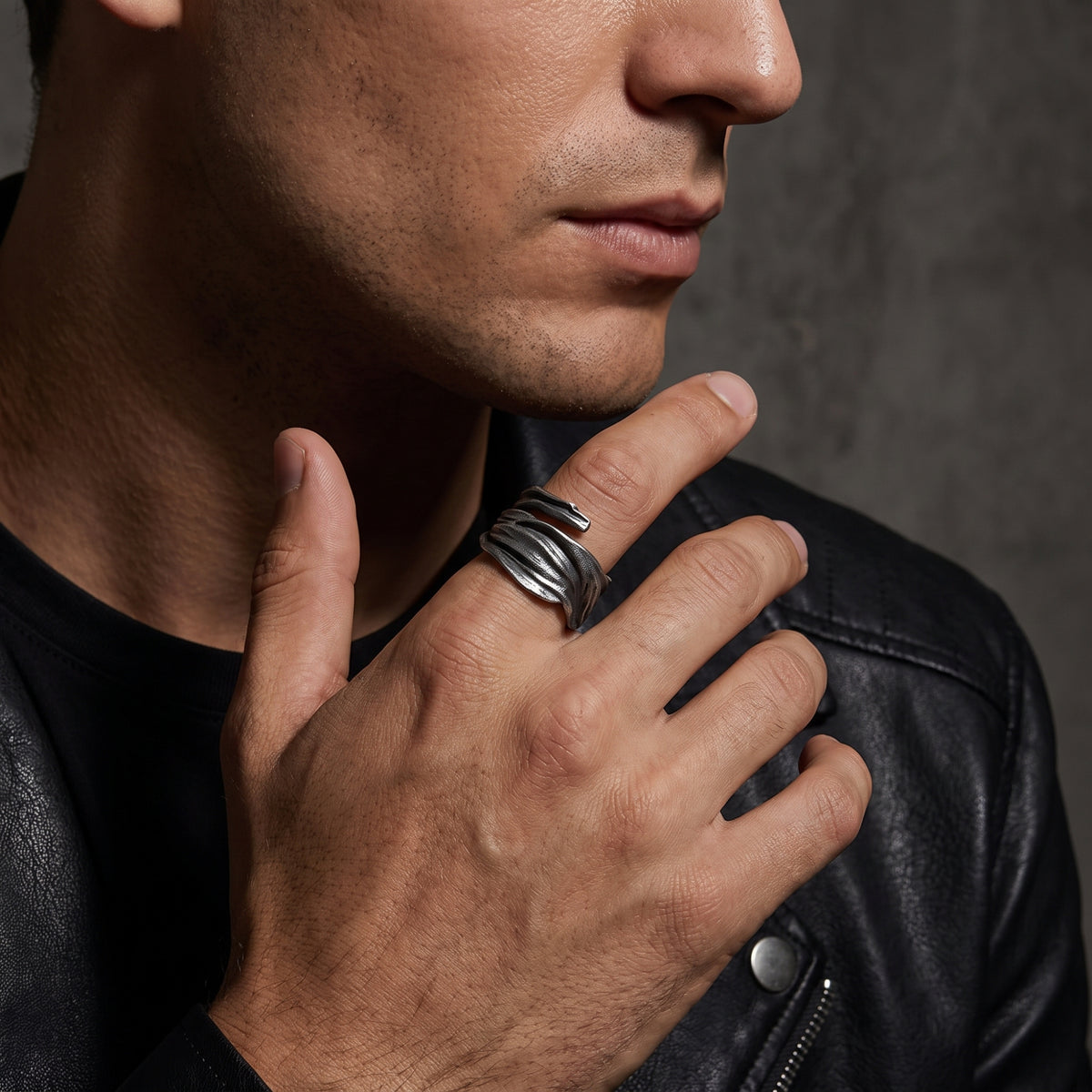Man in a black leather jacket wearing the textured silver open ring on his index finger.