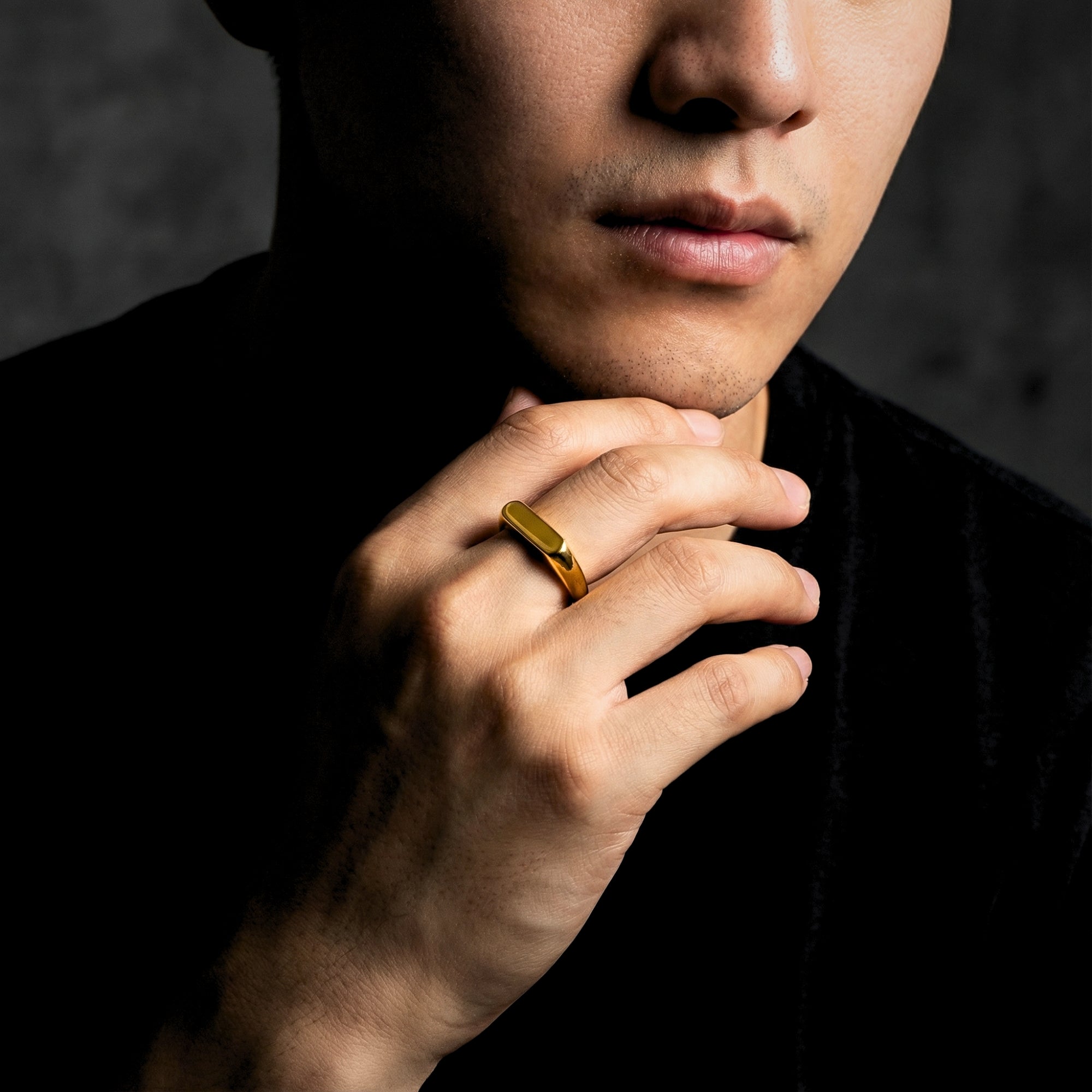Man wearing the gold stainless steel Pillar signet ring on his ring finger, hand held to his chin.