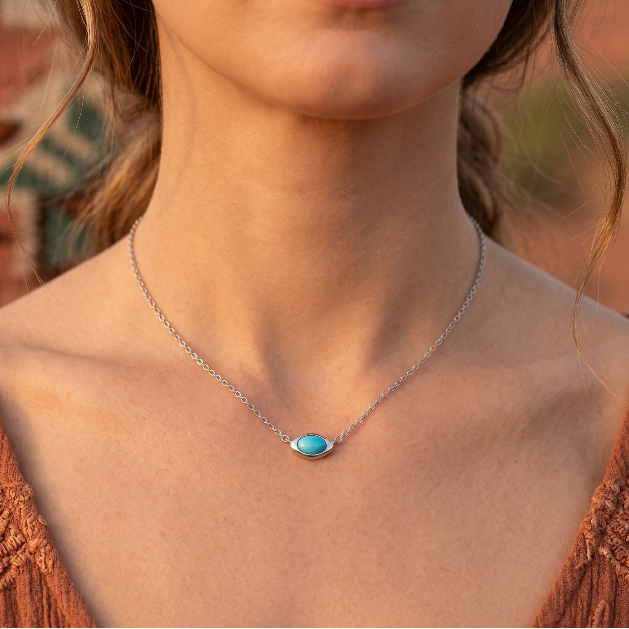 Woman wearing the silver turquoise necklace with a horizontal cabochon pendant against a soft desert background.