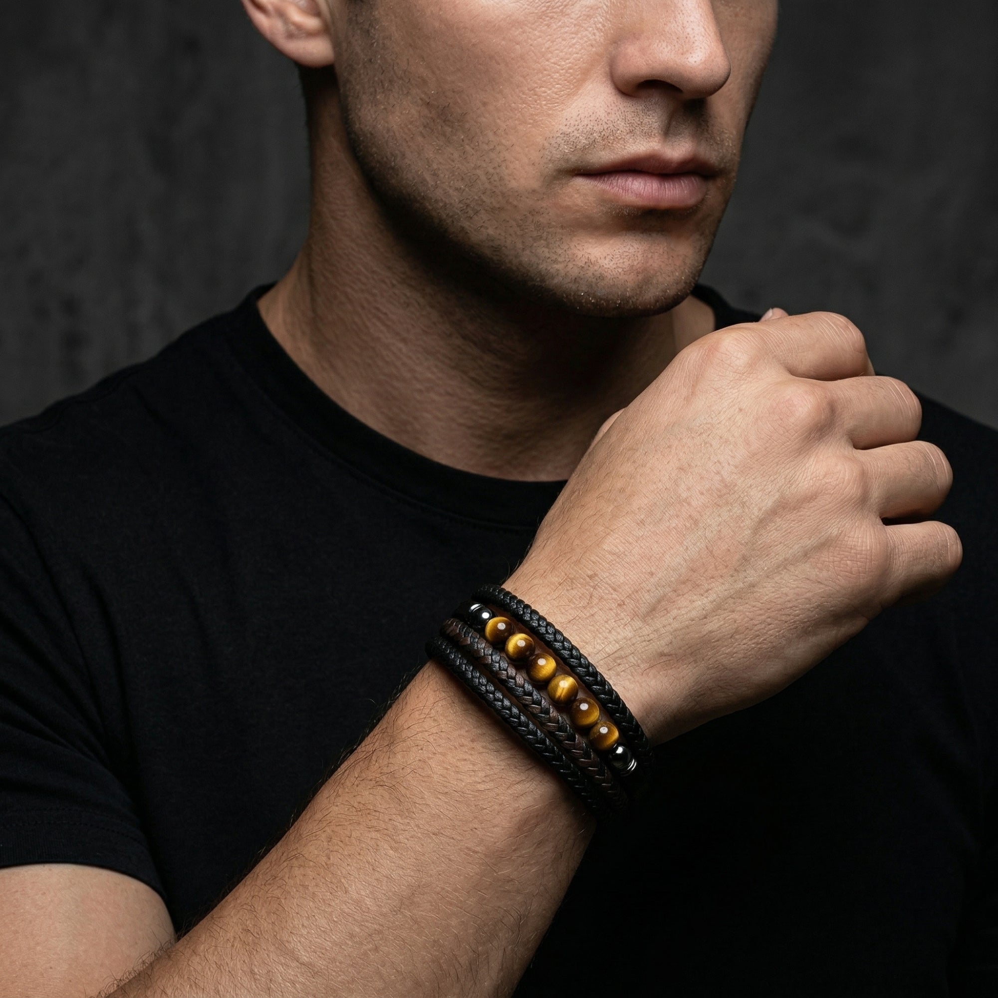Men's black stainless steel and leather bracelet with round yellow tiger eye beads worn on a wrist.