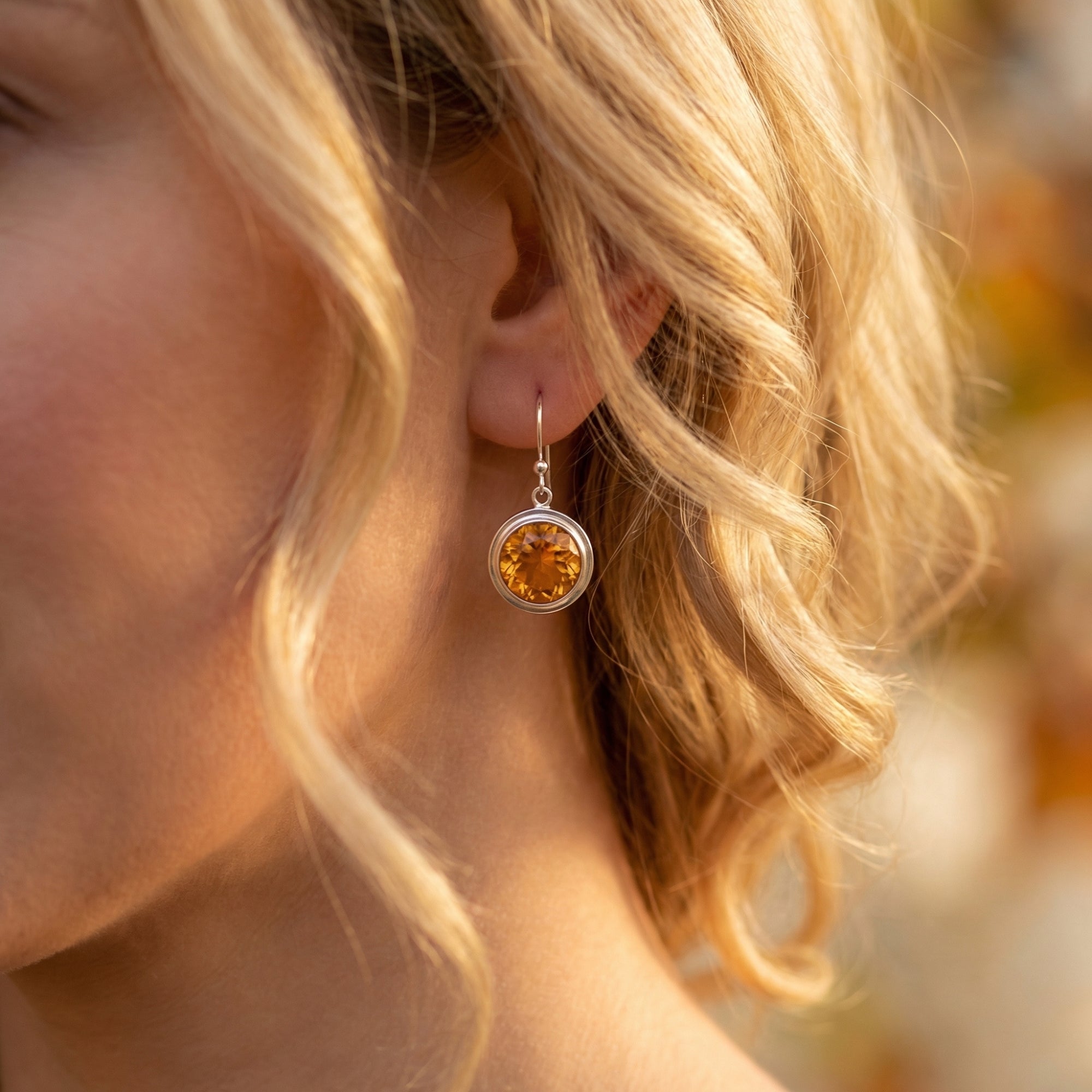 Blonde model wearing a round-cut natural citrine drop earring in sterling silver.