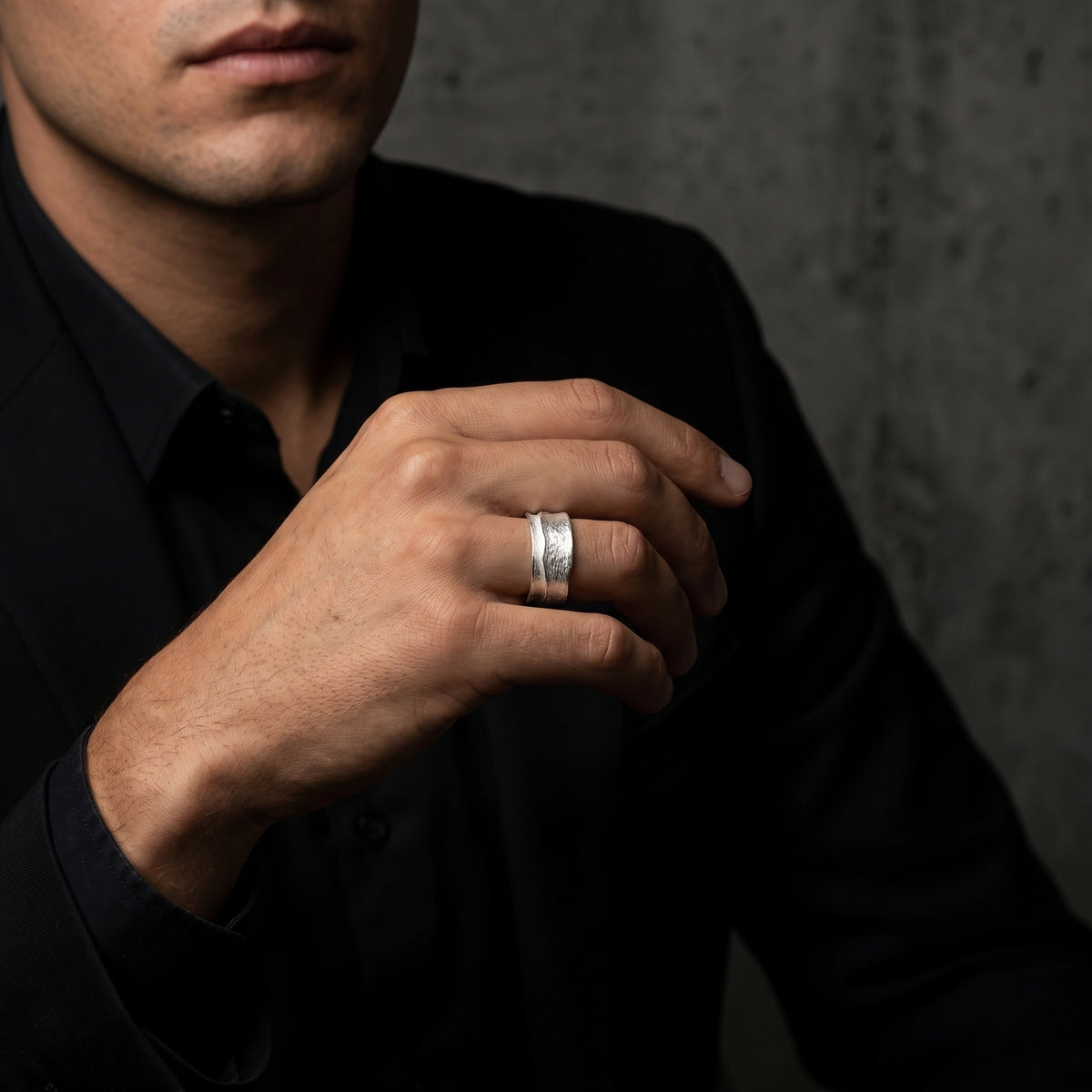 Man in a black jacket wearing the textured silver open-band ring on his ring finger