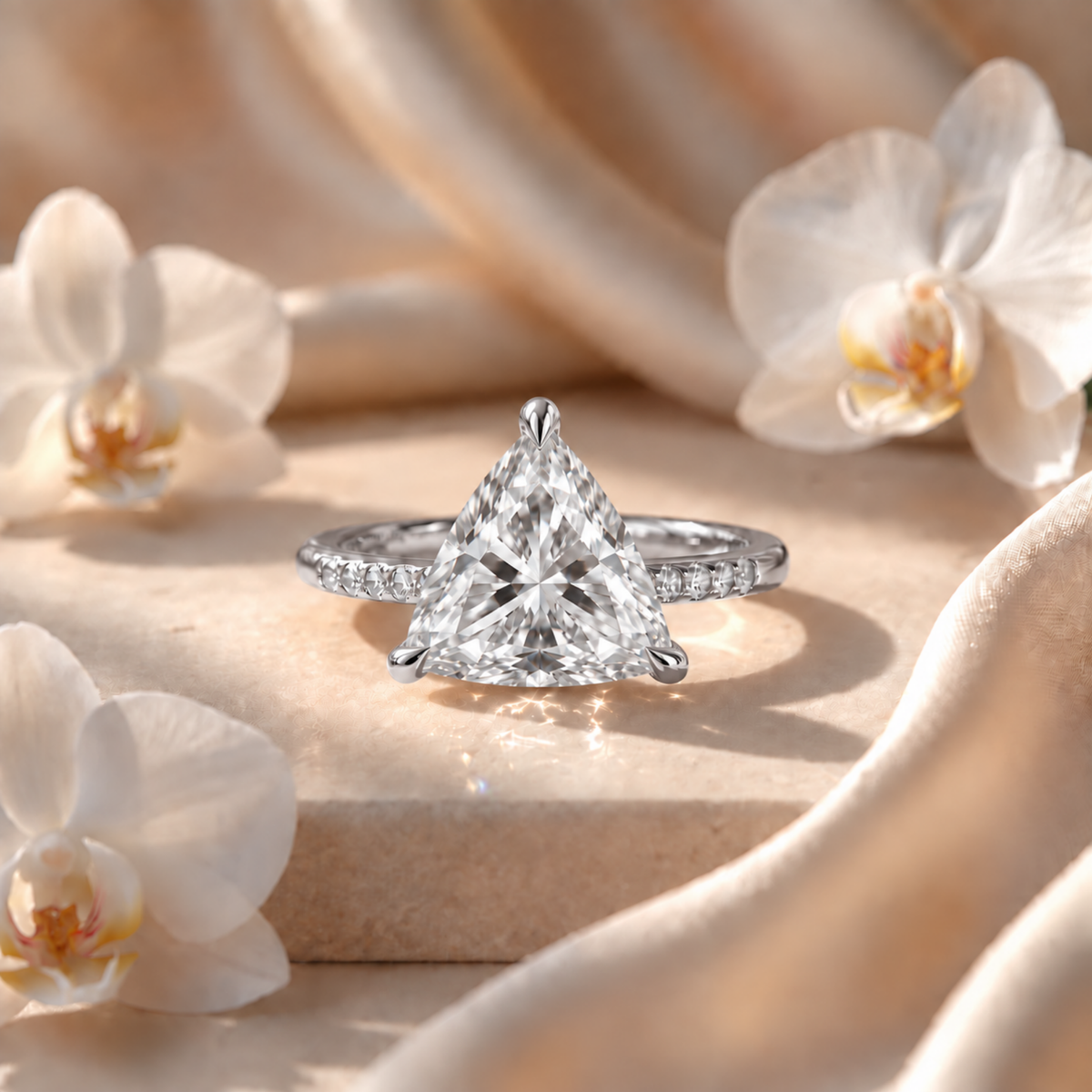 Front view of a white gold trillion-cut moissanite engagement ring with a pavé band.