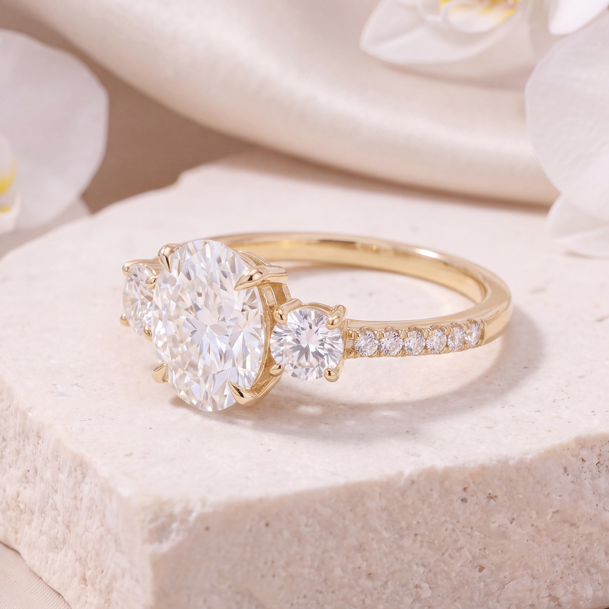Side angle view of a yellow gold three-stone oval moissanite engagement ring.