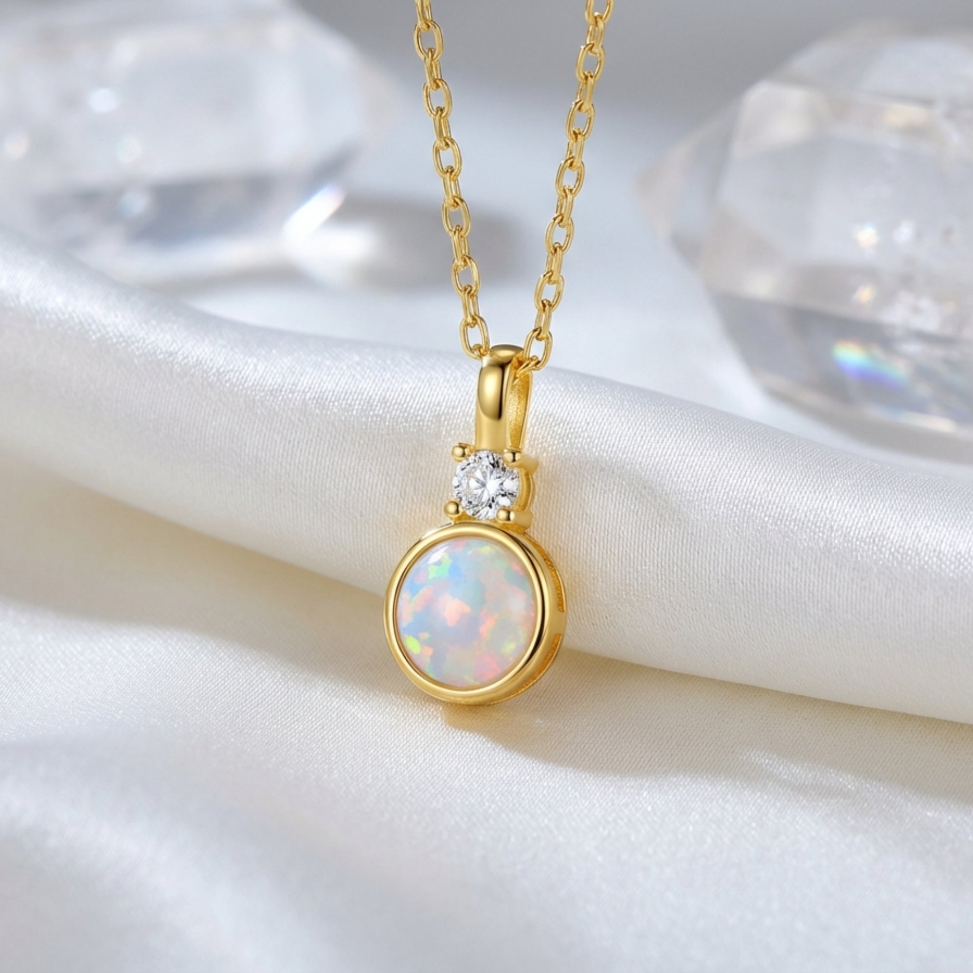 Macro shot of the yellow gold Lariel pendant showing the round white opal and clear accent stone.