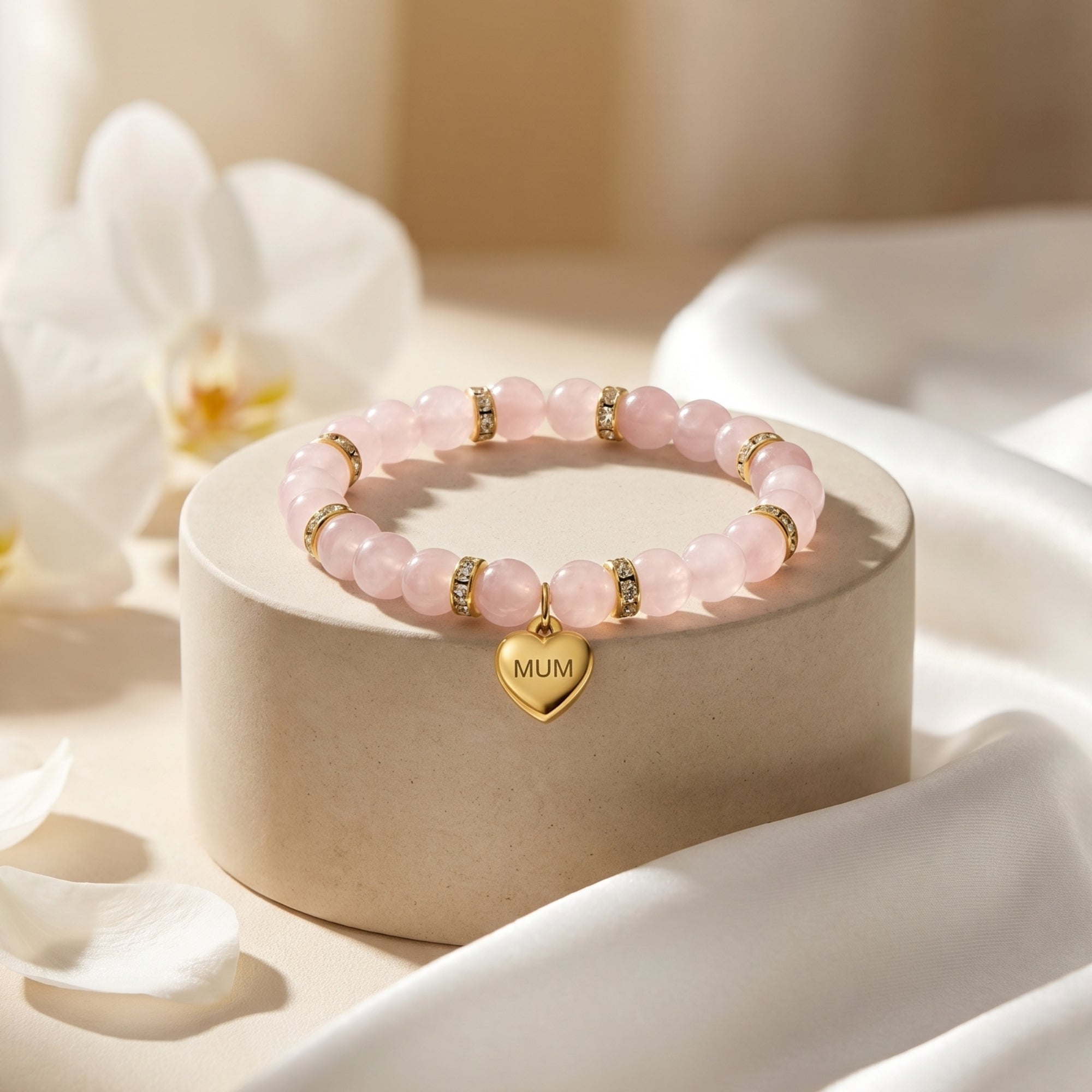 18K gold finish rose quartz bracelet with MUM heart charm on a round pedestal with floral accents.