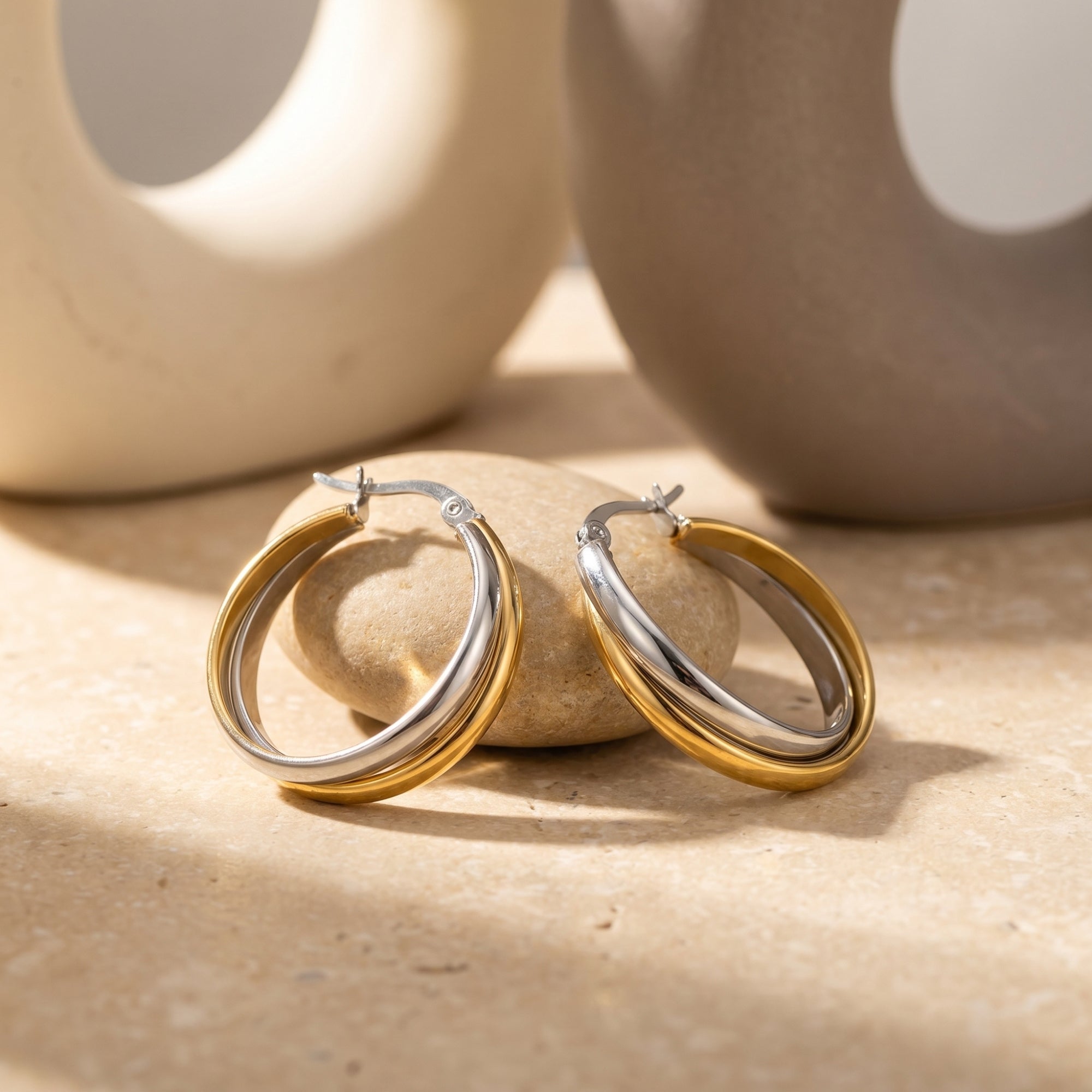 Pair of silver and 18K gold-plated interlocking huggie earrings in a styled setting.