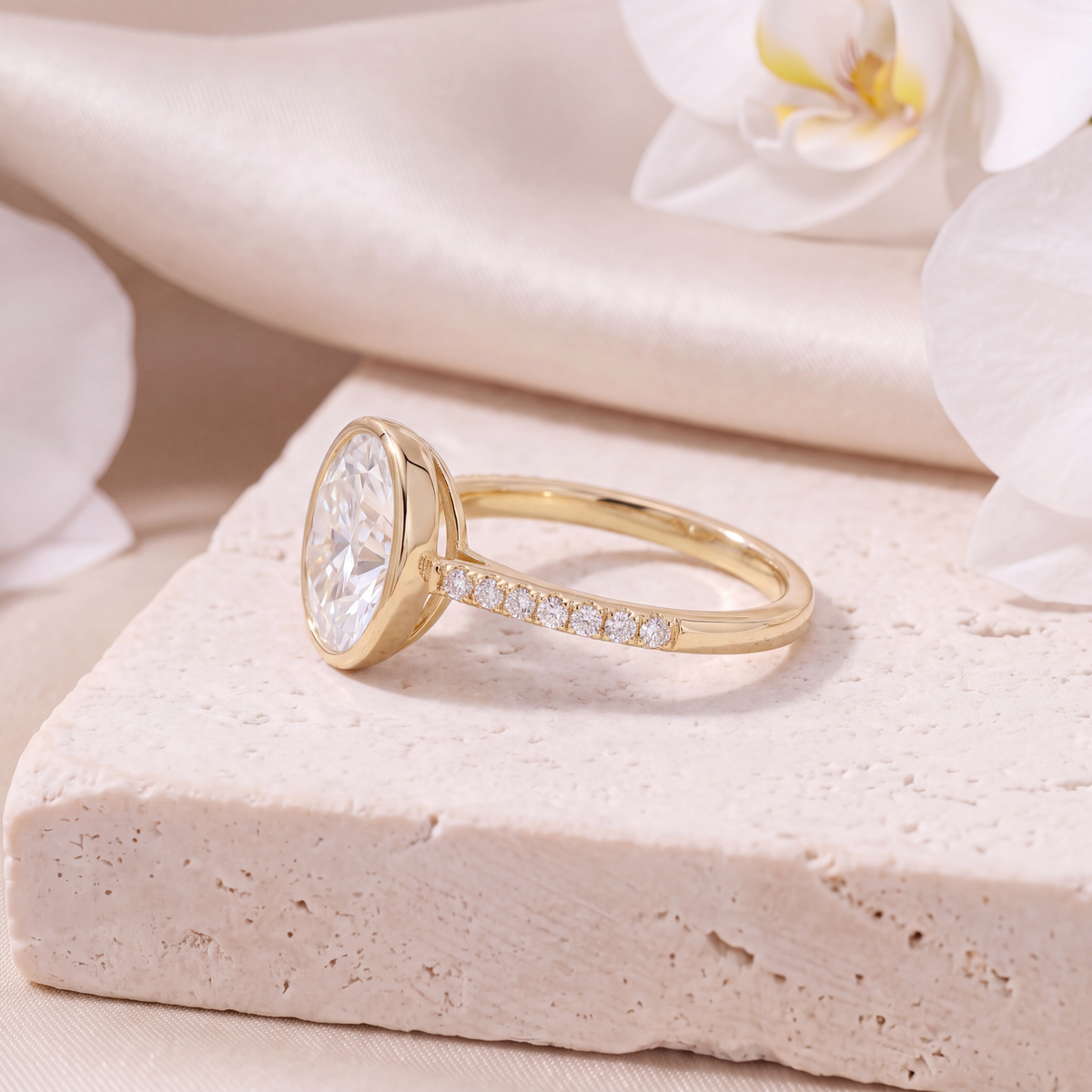 Side view profile of a gold bezel-set oval moissanite ring with a pavé band.