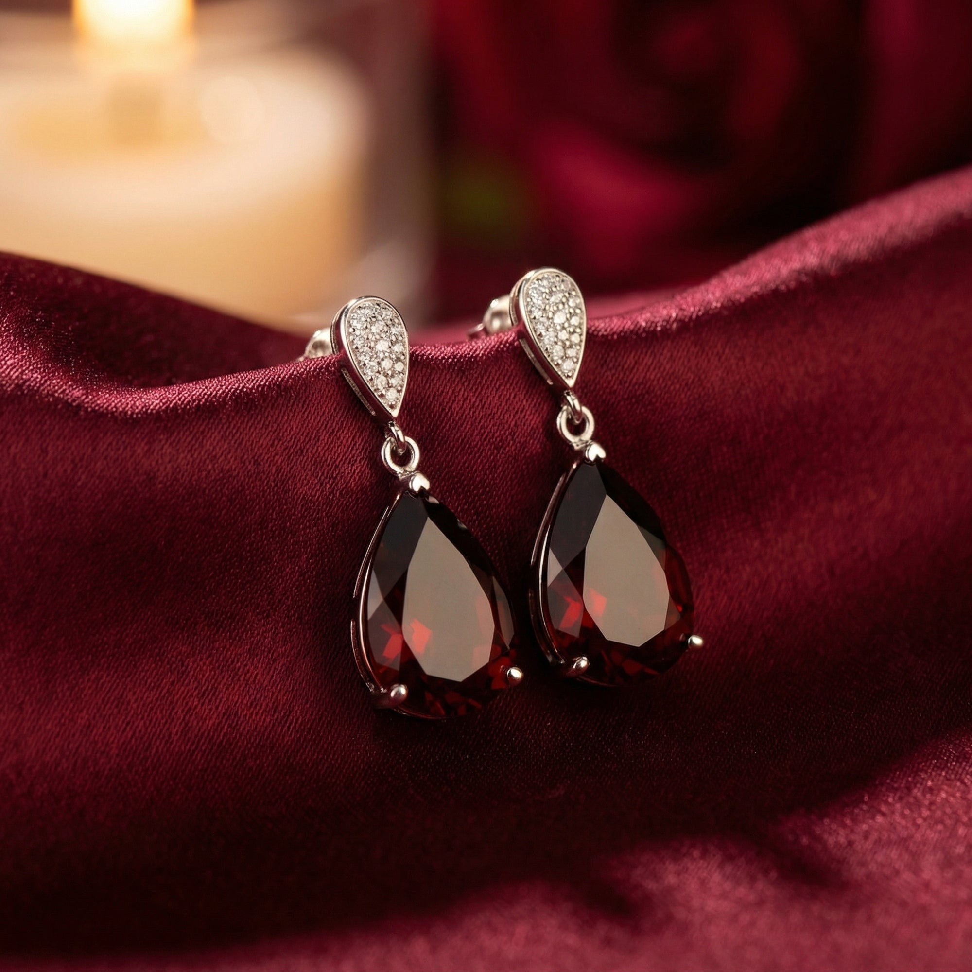 Close-up of sterling silver drop earrings showcasing the rich burgundy color of the 8x12mm pear cut natural garnets.
