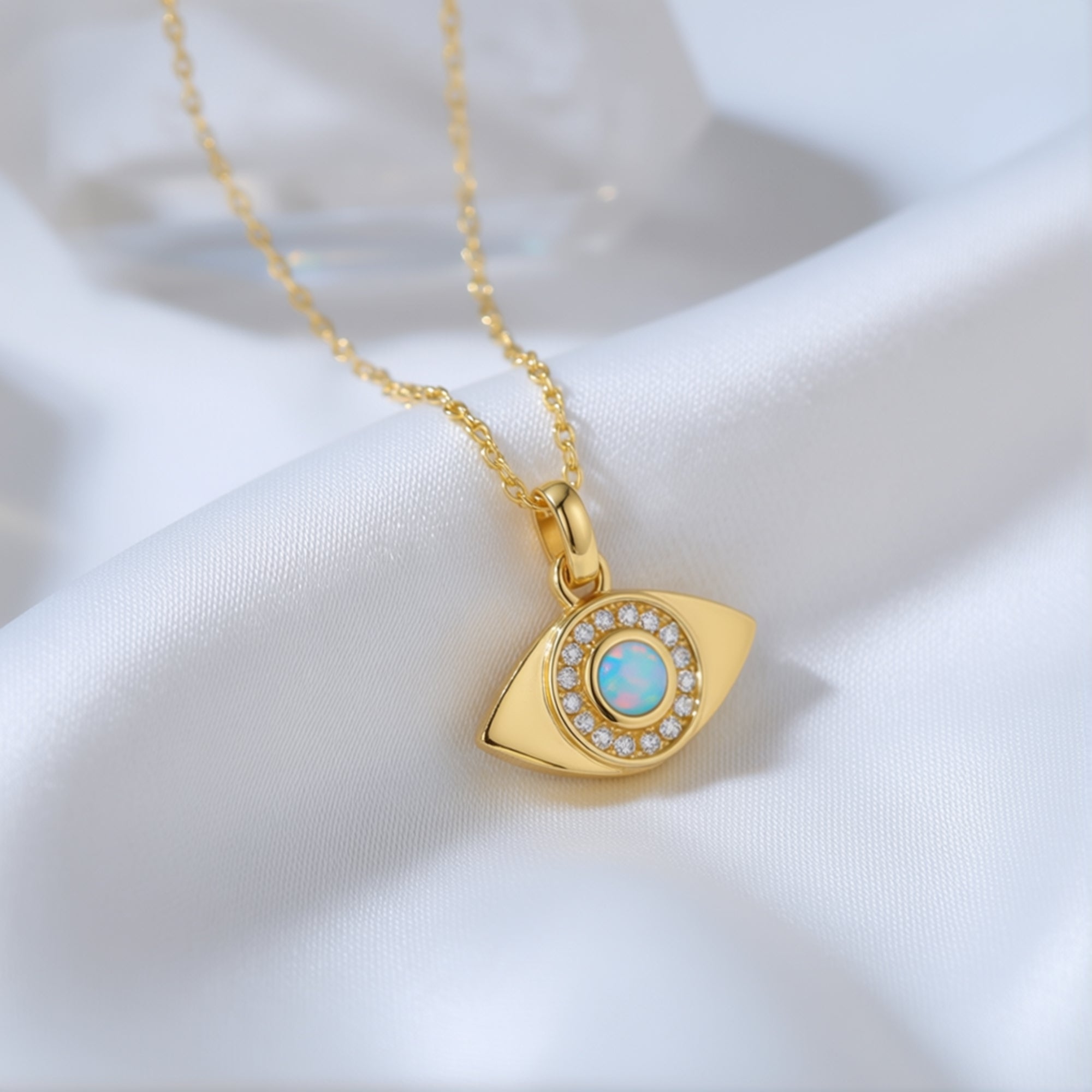 Macro view of the gold evil eye pendant featuring a round white opal and shimmering pavé accents.