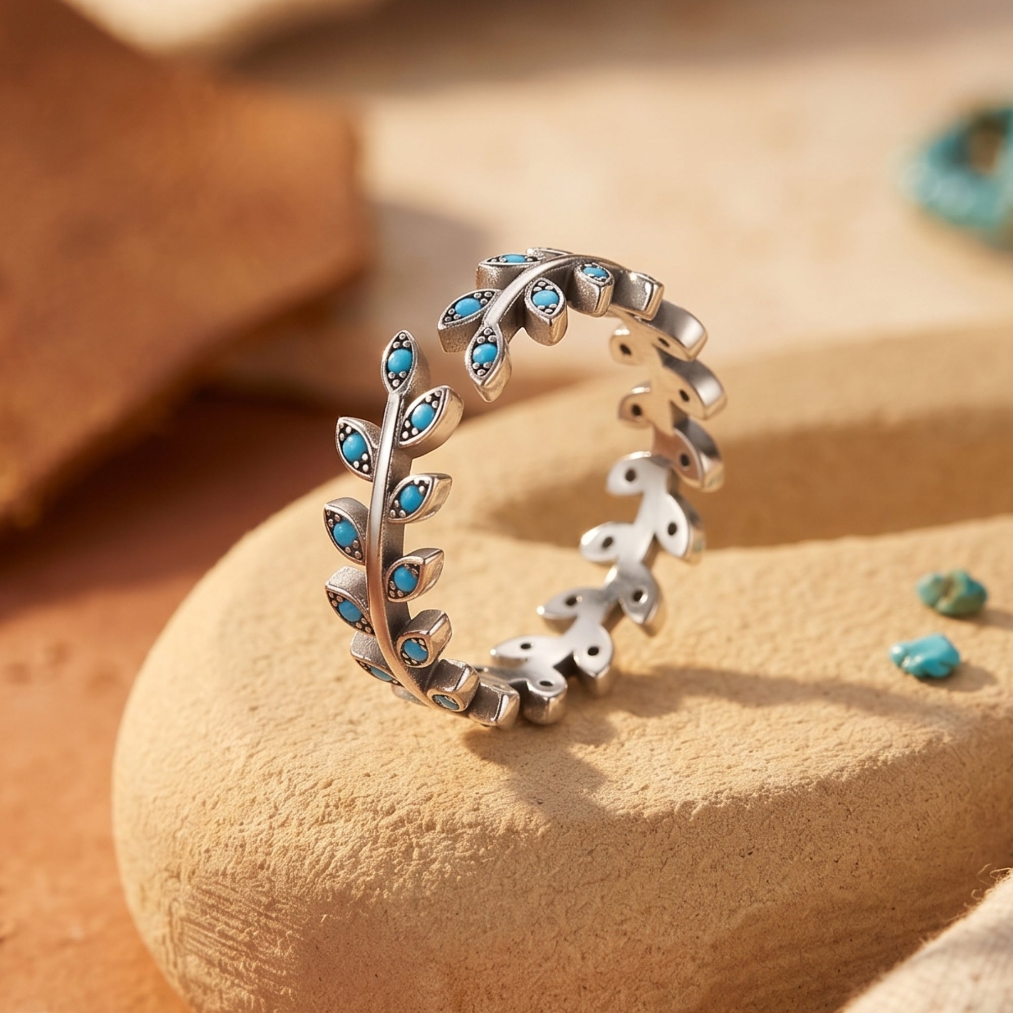 Macro view of the sterling silver leaf ring showing detailed sculpting and small turquoise stone settings.
