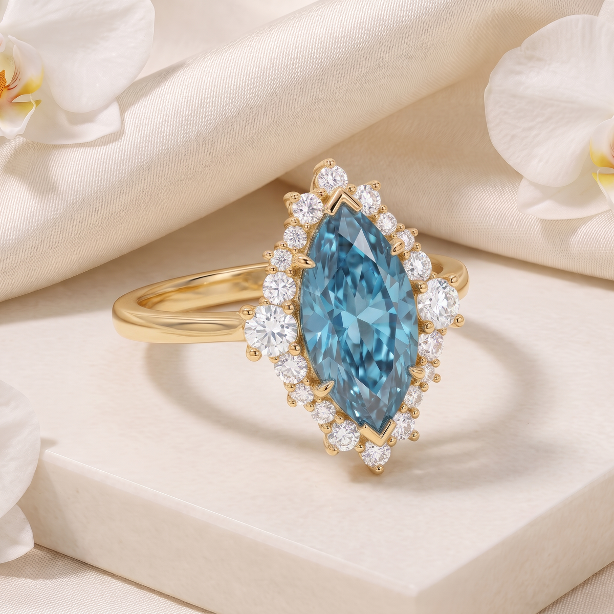 Angled perspective view of a marquise-cut blue moissanite halo ring in yellow gold on a display pedestal.