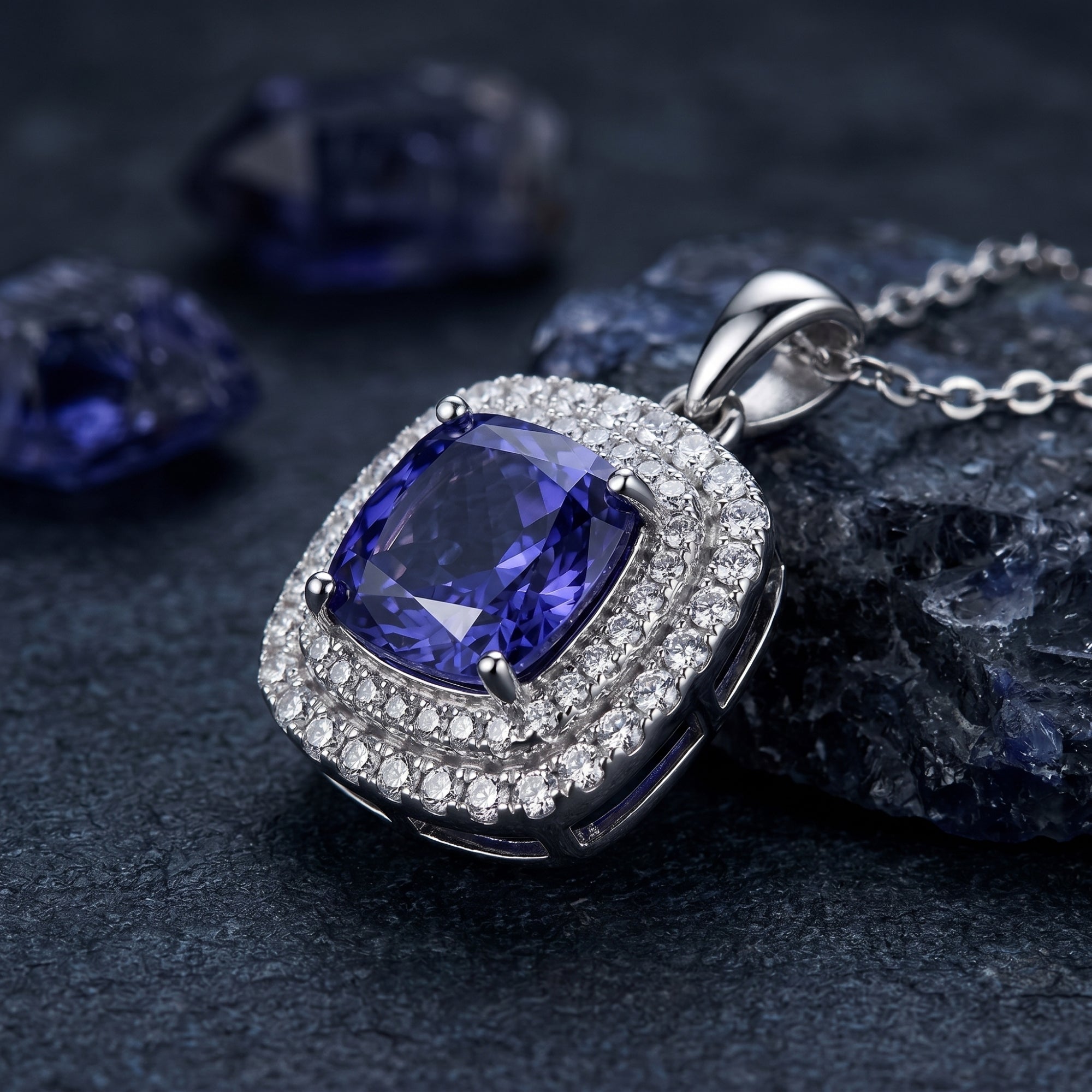 Macro view of a cushion cut tanzanite pendant with a double halo of white stones in a silver setting.