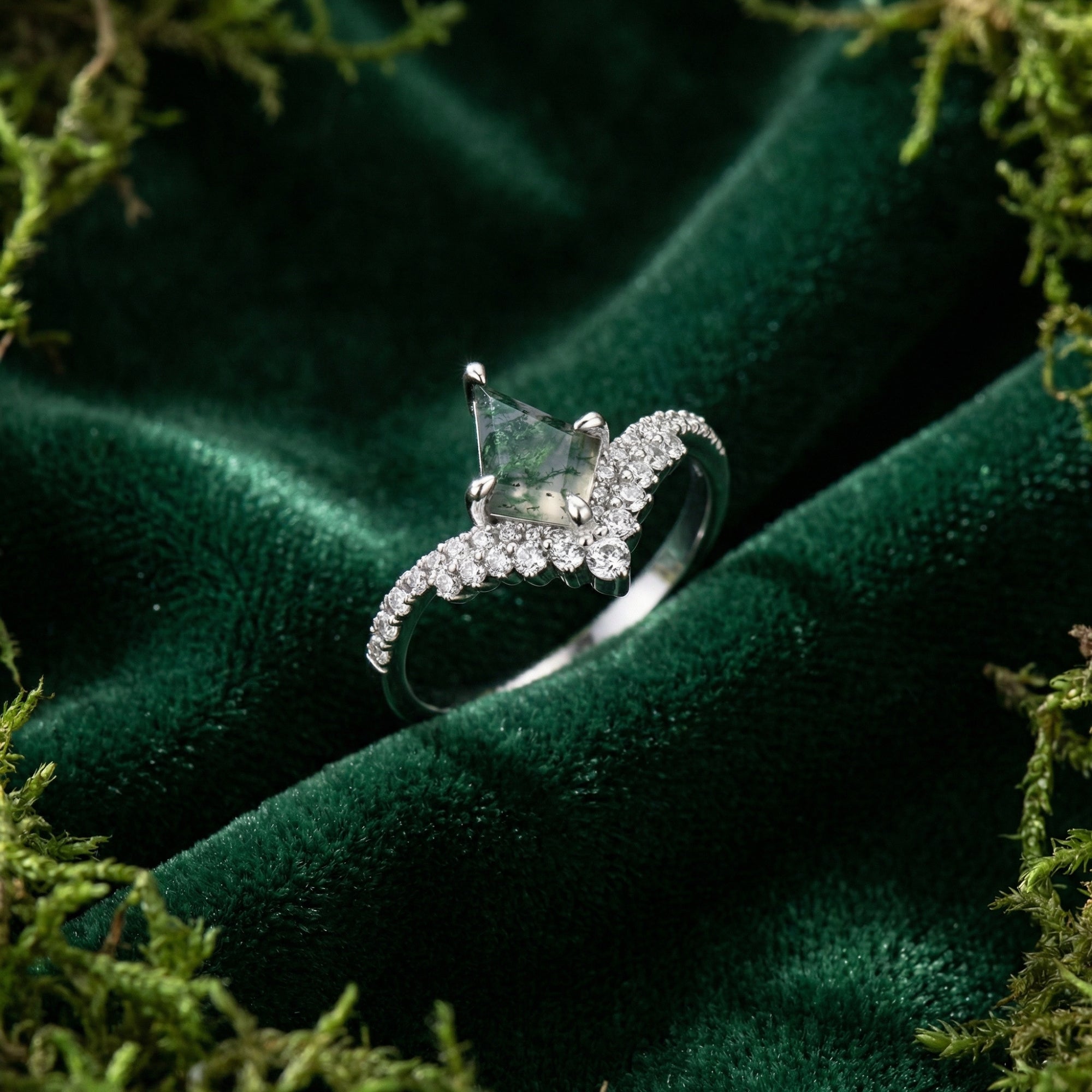 Angled view of the kite cut moss agate ring with a diamond chevron band in S925 sterling silver on green velvet.