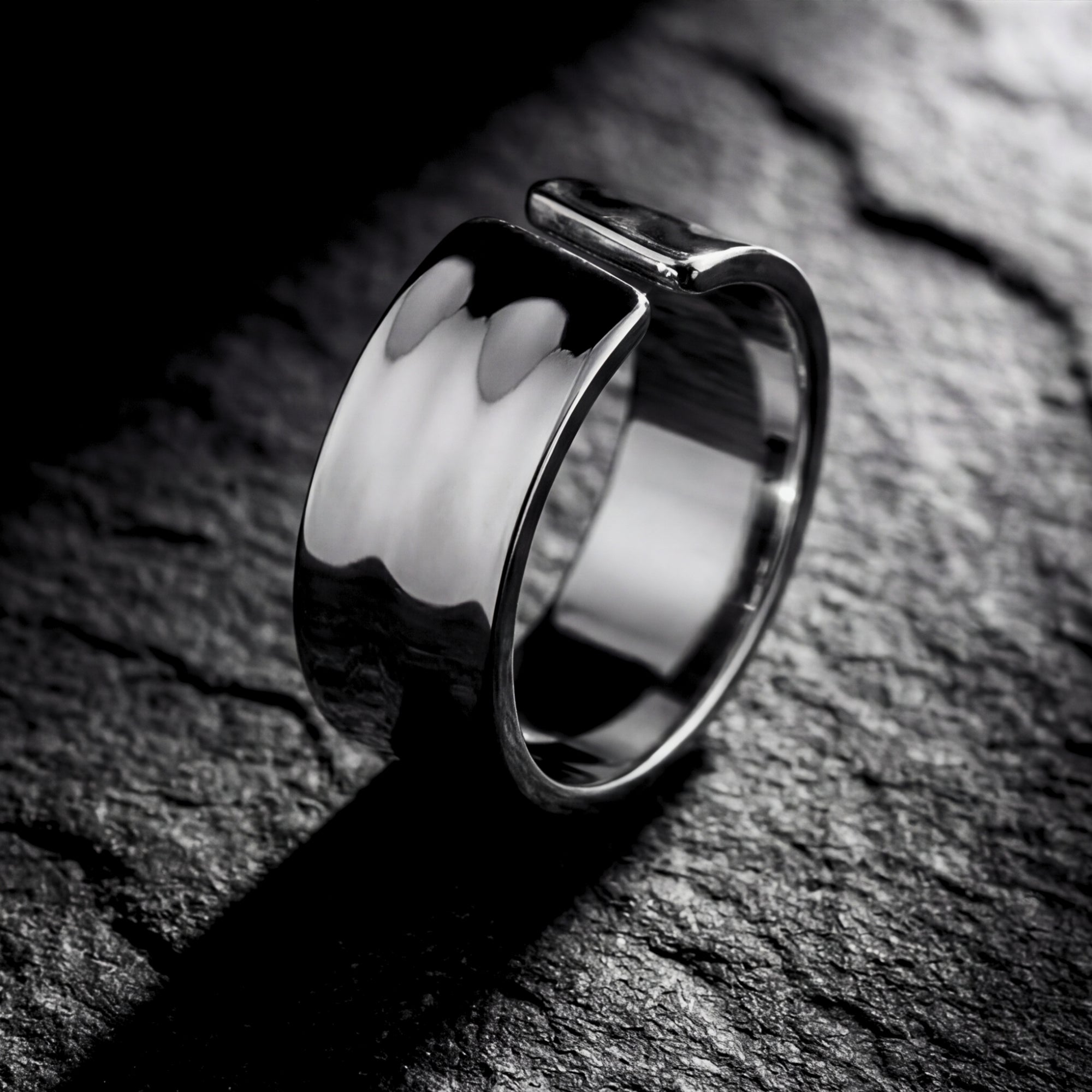 Side profile of the silver stainless steel Origin Flex adjustable ring on a dark stone surface.