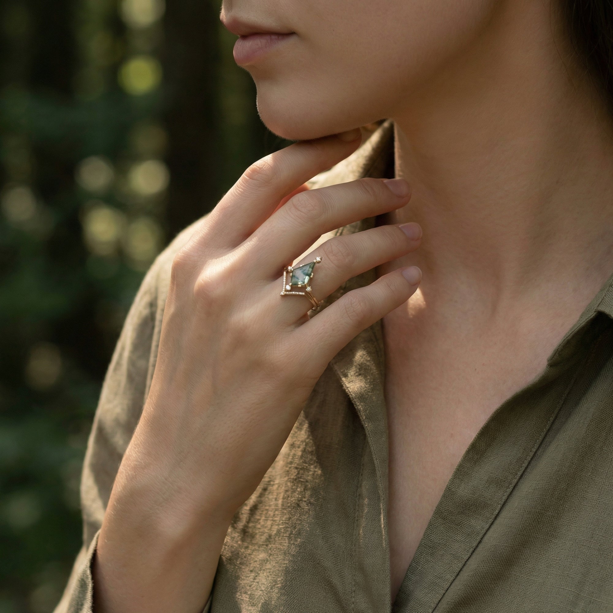 Model wearing the kite cut moss agate gold ring set on her ring finger in soft natural light.