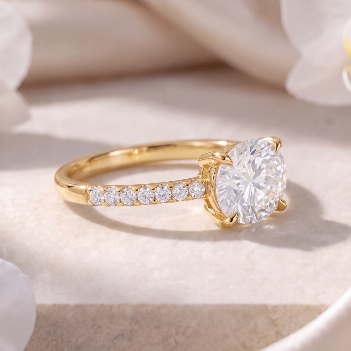 Side view of a yellow gold east-west oval moissanite engagement ring featuring a pave set band.