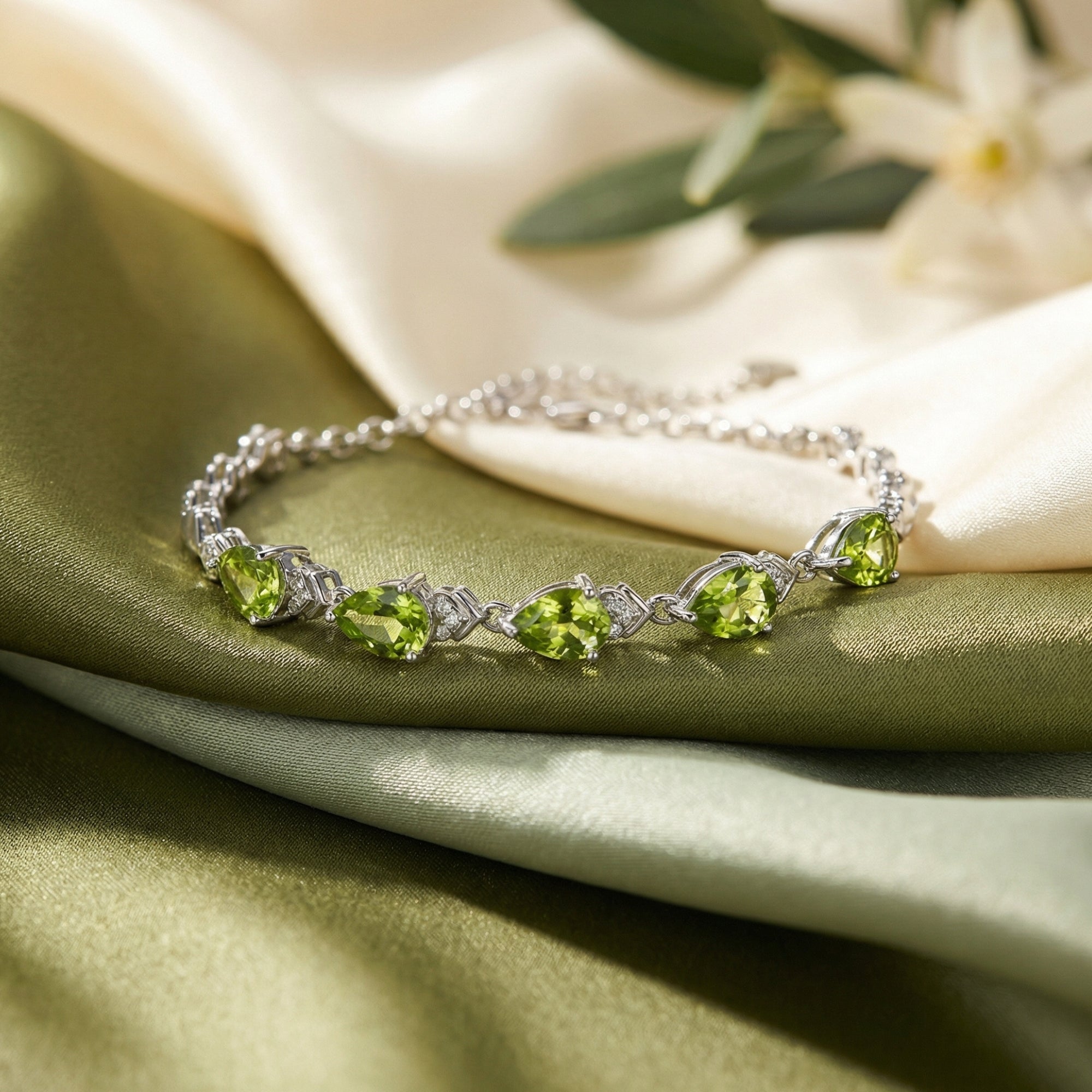 Macro view of pear-cut green peridot stones and sterling silver settings on a delicate station bracelet.
