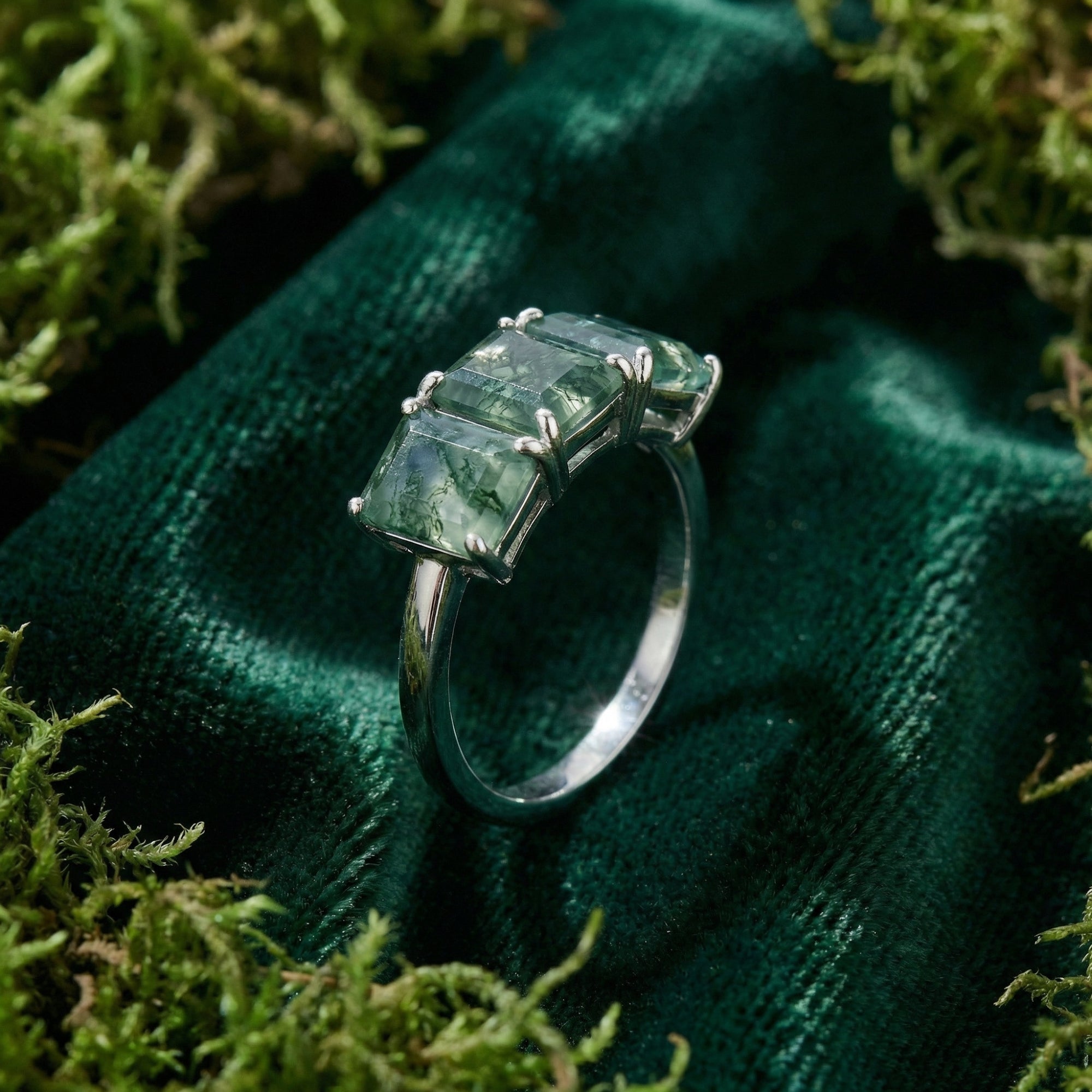 Side view of the triple moss agate bar ring in S925 sterling silver on a green velvet and moss background.