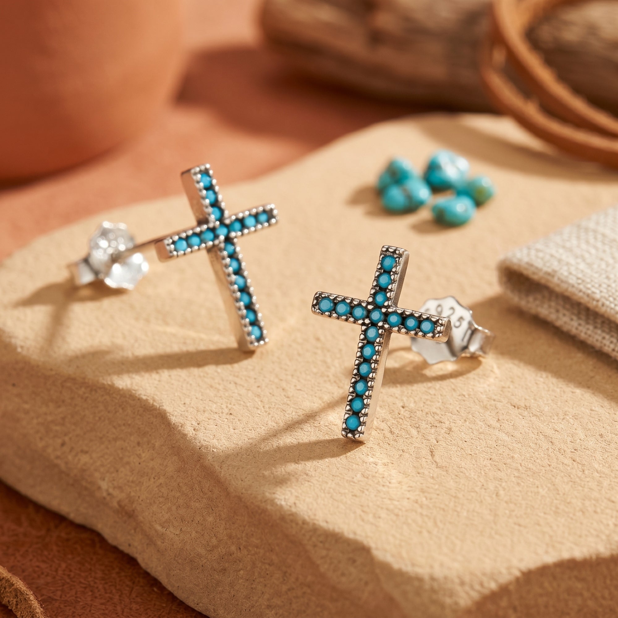 Macro view of sterling silver cross earrings featuring small, round robin's-egg blue turquoise stones.