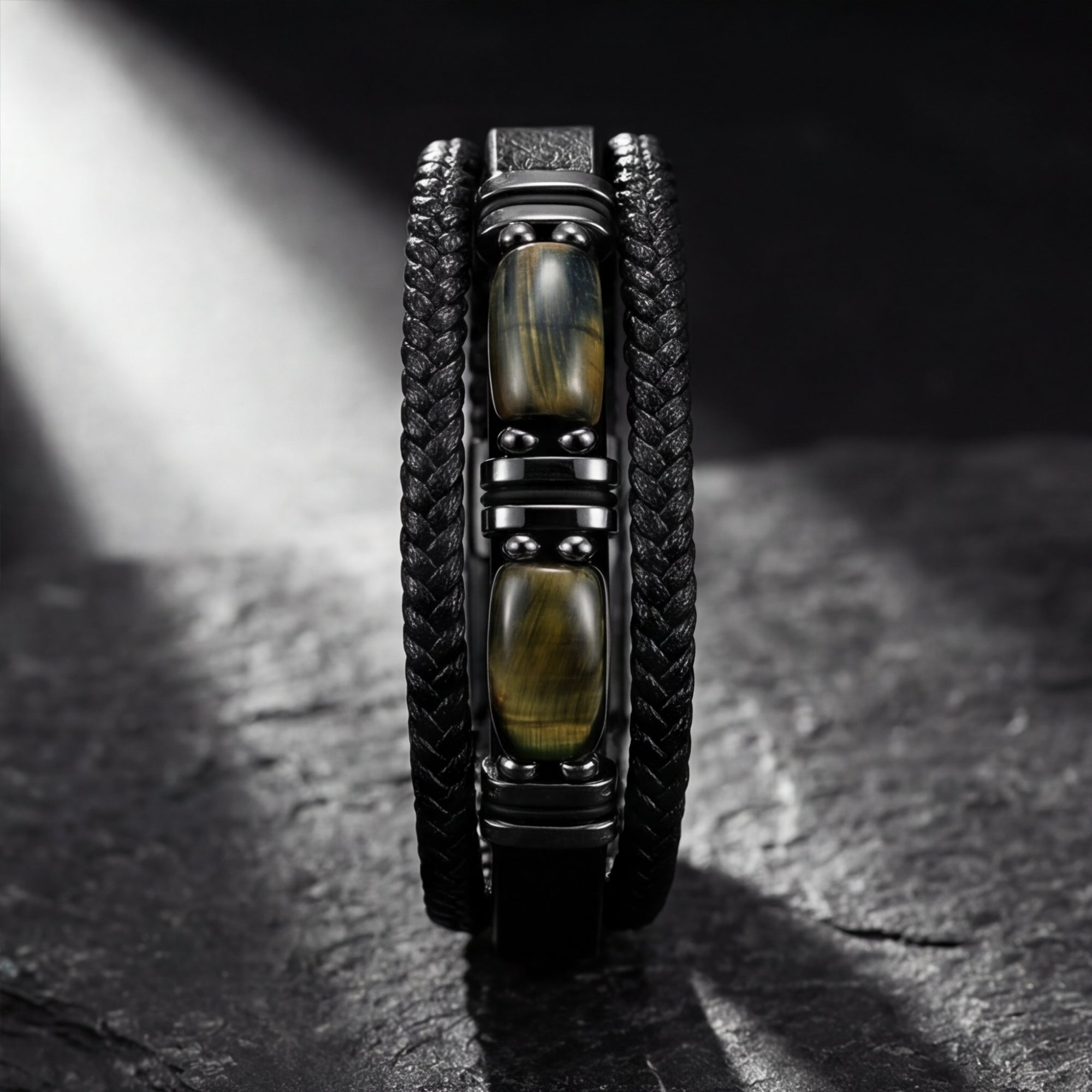 Macro view of tiger's eye stones and black stainless steel accents on a multi-layered black leather bracelet.