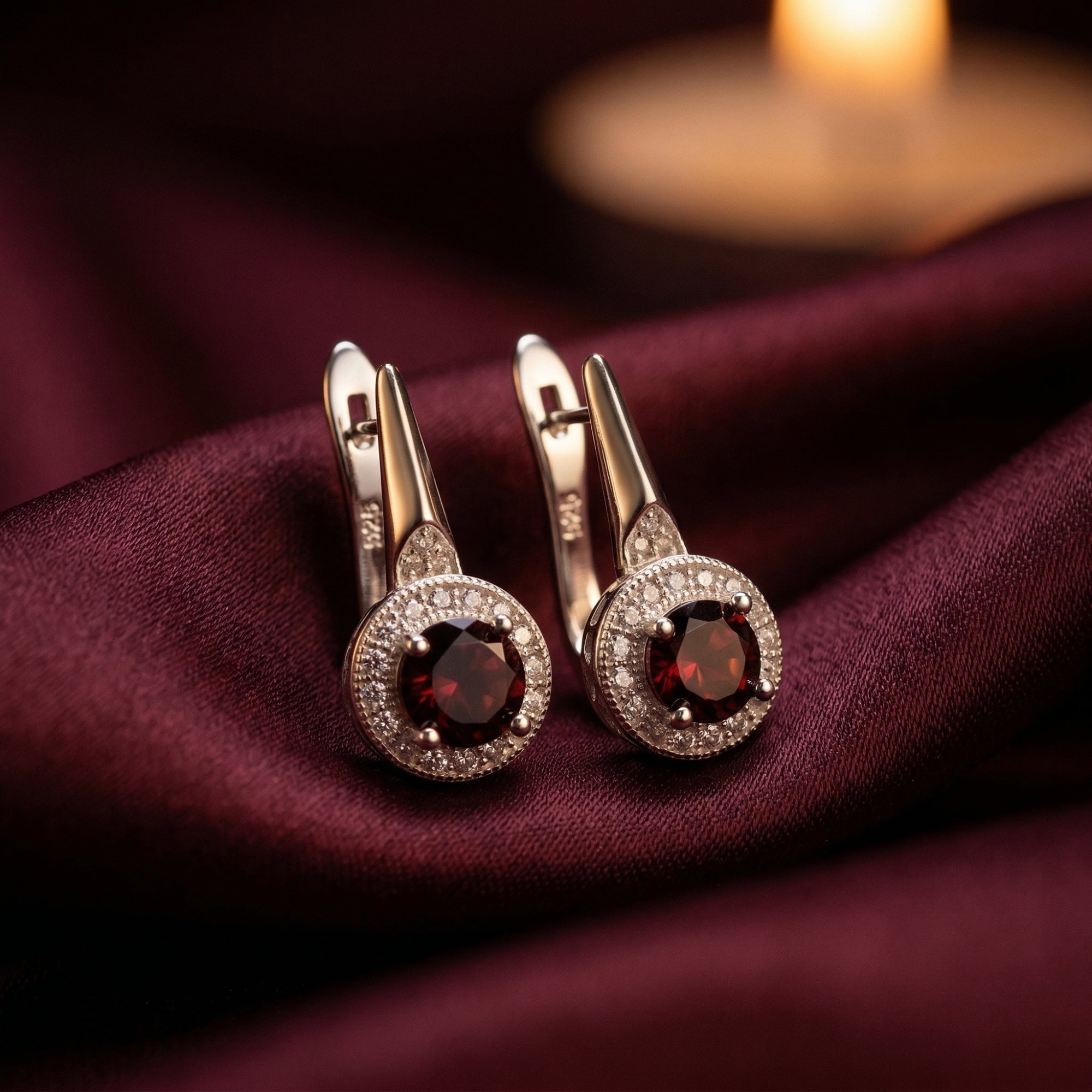 Macro view of S925 sterling silver drop earrings with round natural garnets and a brilliant halo.