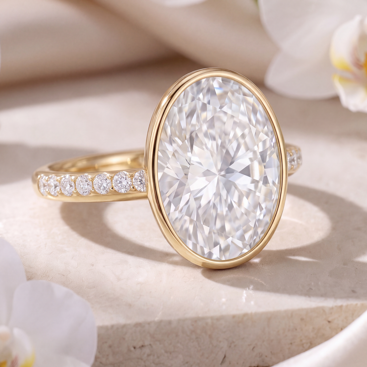 Close-up perspective view of an oval moissanite bezel engagement ring in yellow gold showing the pave band.
