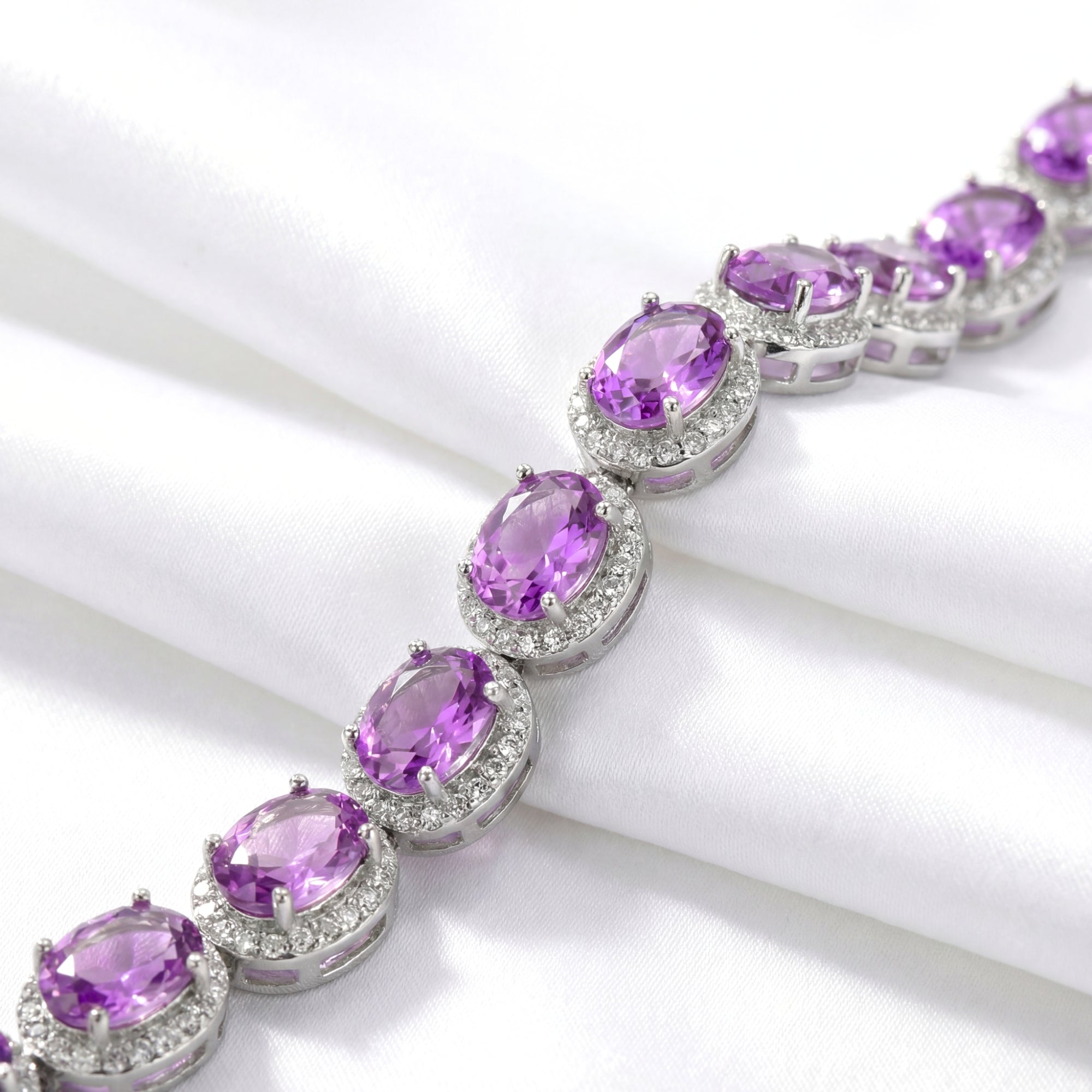 Close-up of oval-cut simulated amethyst stones and halo settings in a sterling silver bracelet.