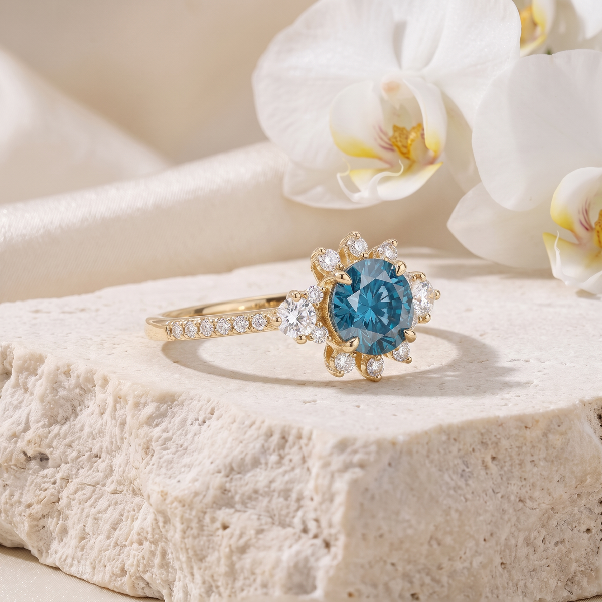 Angled view of a yellow gold starburst halo moissanite ring with a brilliant blue center stone on a stone slab.