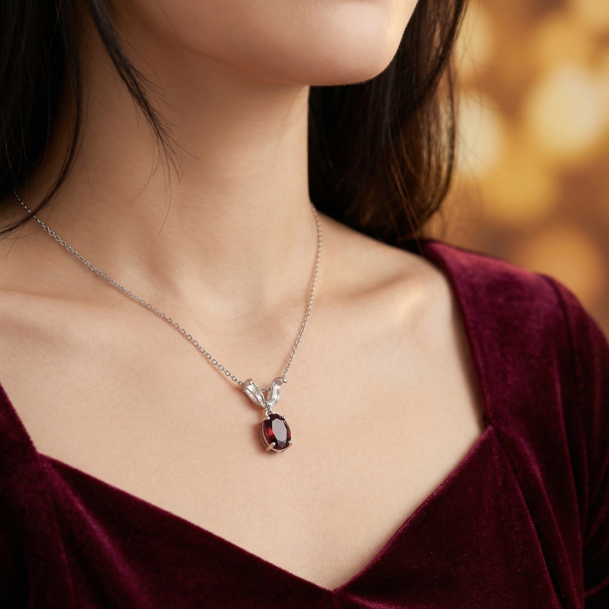 Model wearing the Veralina oval natural garnet necklace in silver, paired with a burgundy velvet dress.