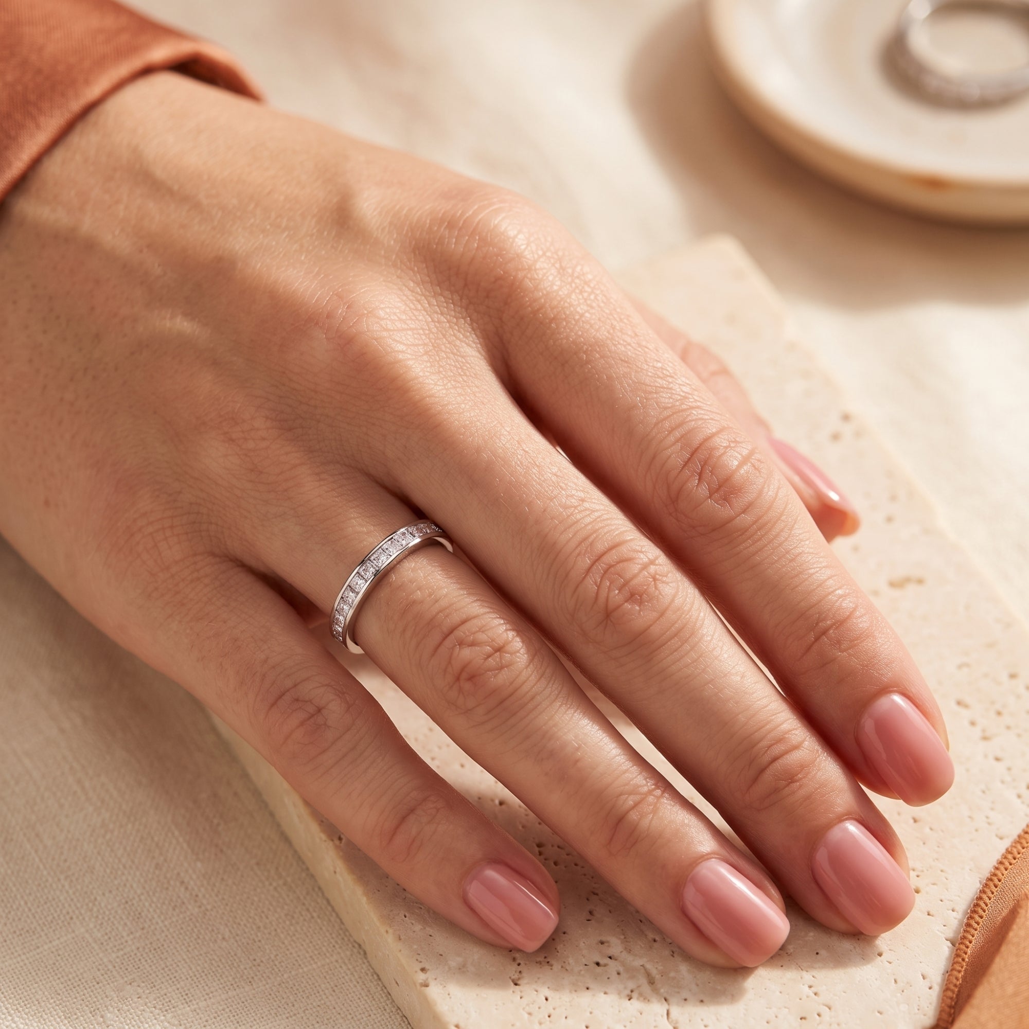 Princess cut cubic zirconia eternity ring in sterling silver shown on a hand for scale.