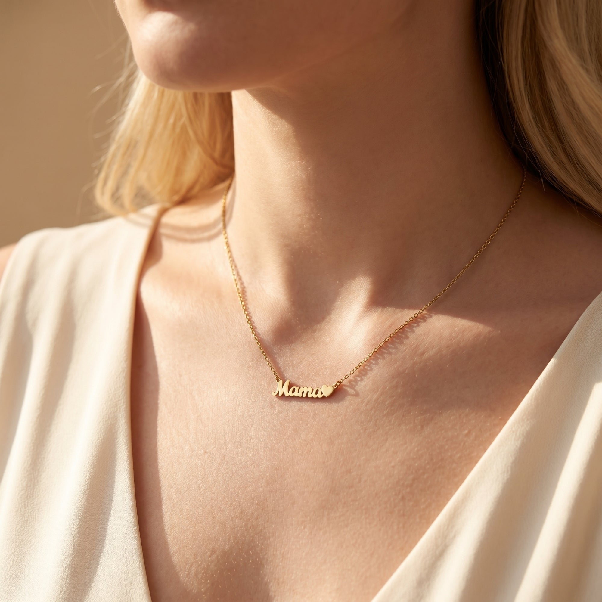 Close-up of a model wearing the 18K gold finish Mama script necklace with heart pendant.
