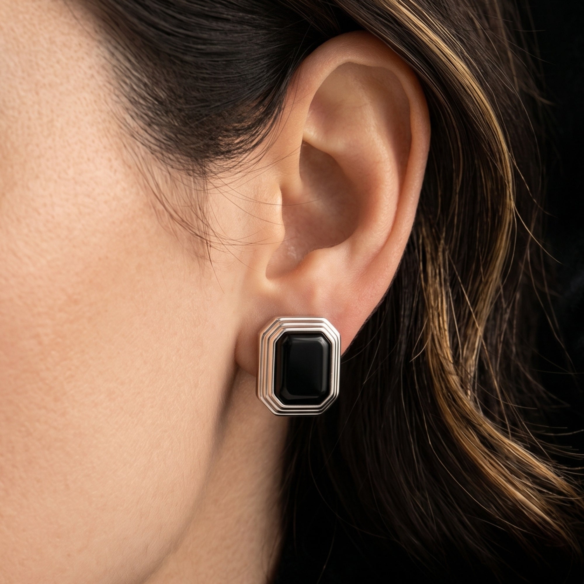 Close-up of a large square cut natural black onyx earring in silver, styled on a model's ear for a bold statement look.