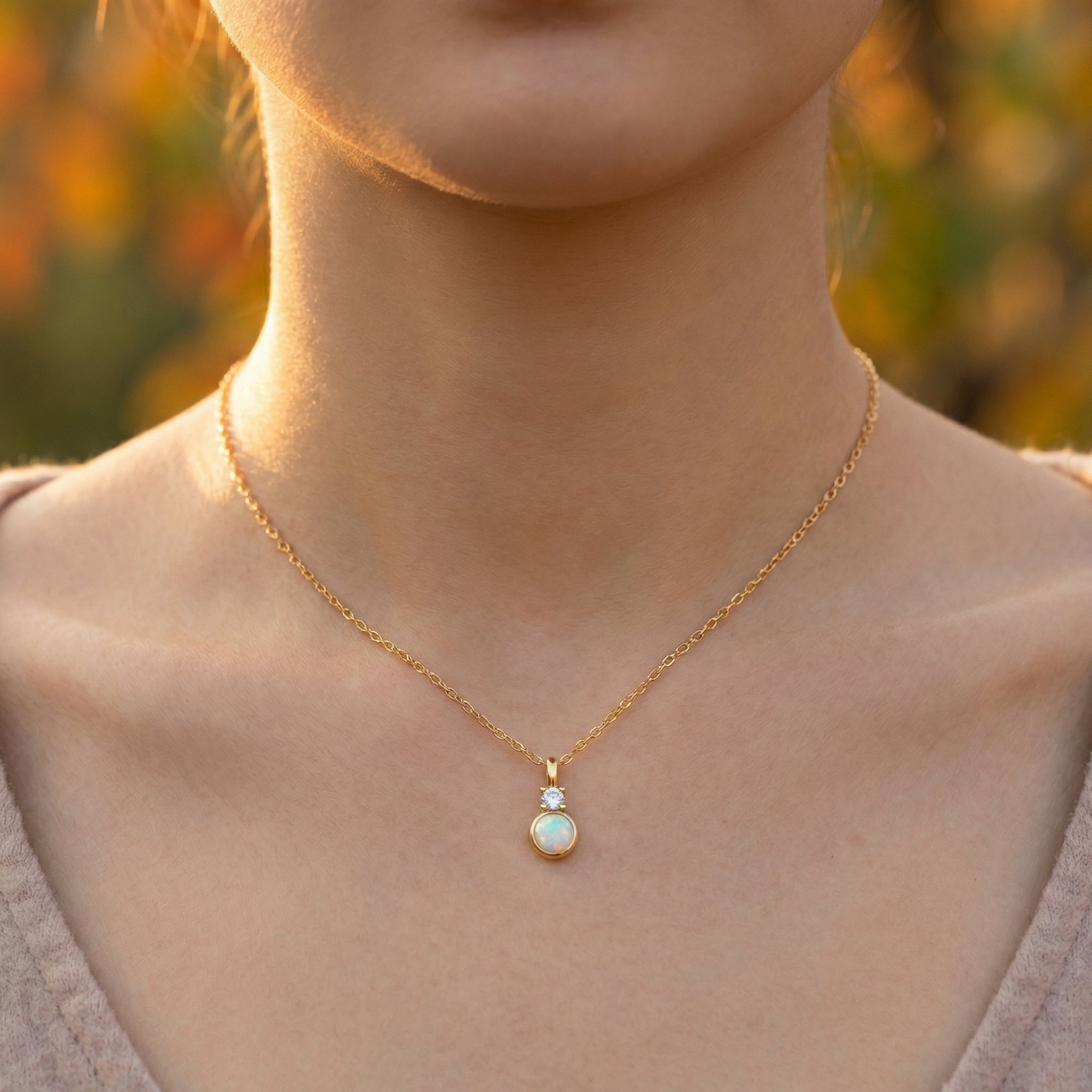 Front view of a model wearing the yellow gold Lariel necklace featuring a round white opal pendant.